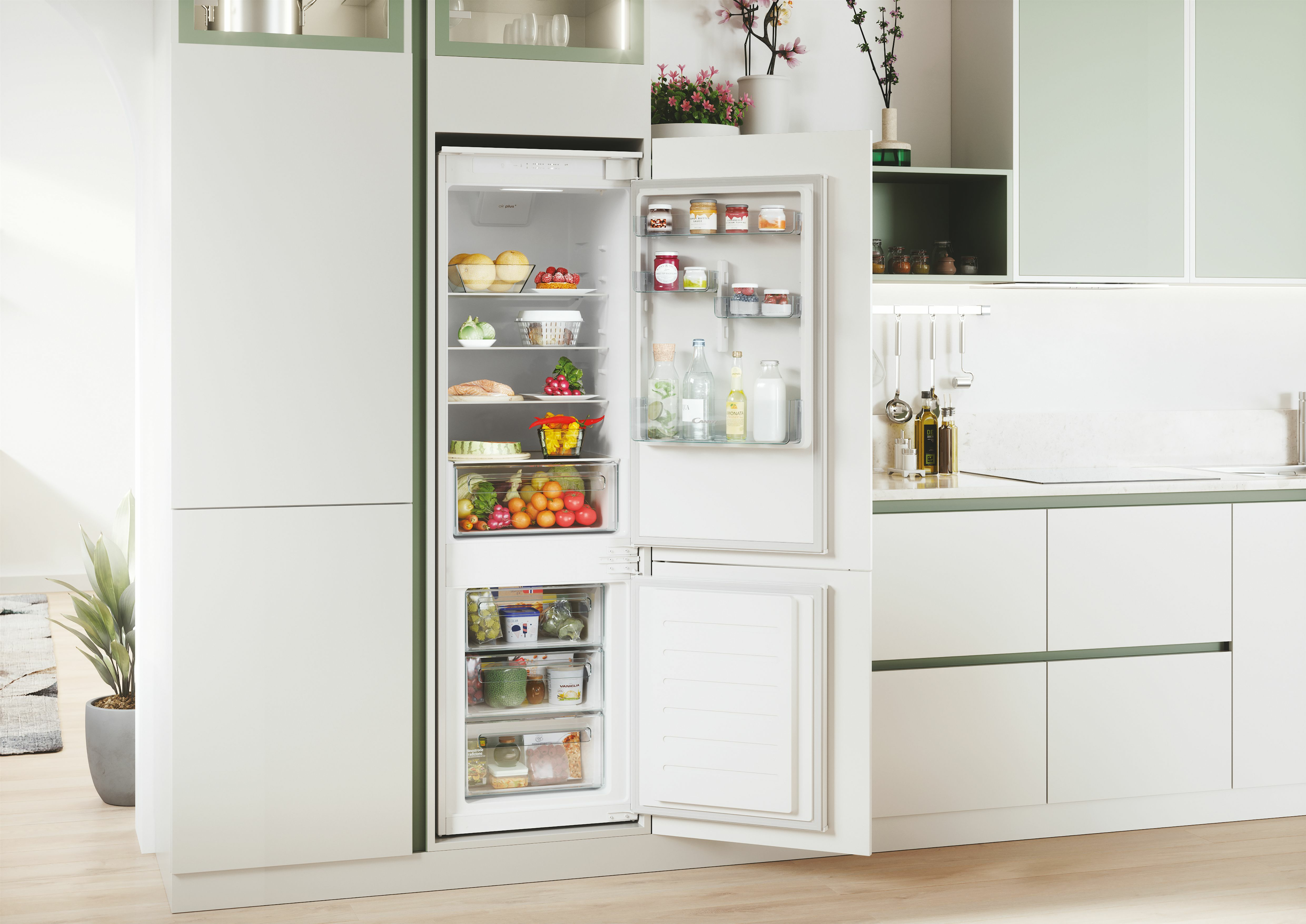 Refrigerador abierto con comida y cajones congeladores en una cocina moderna.