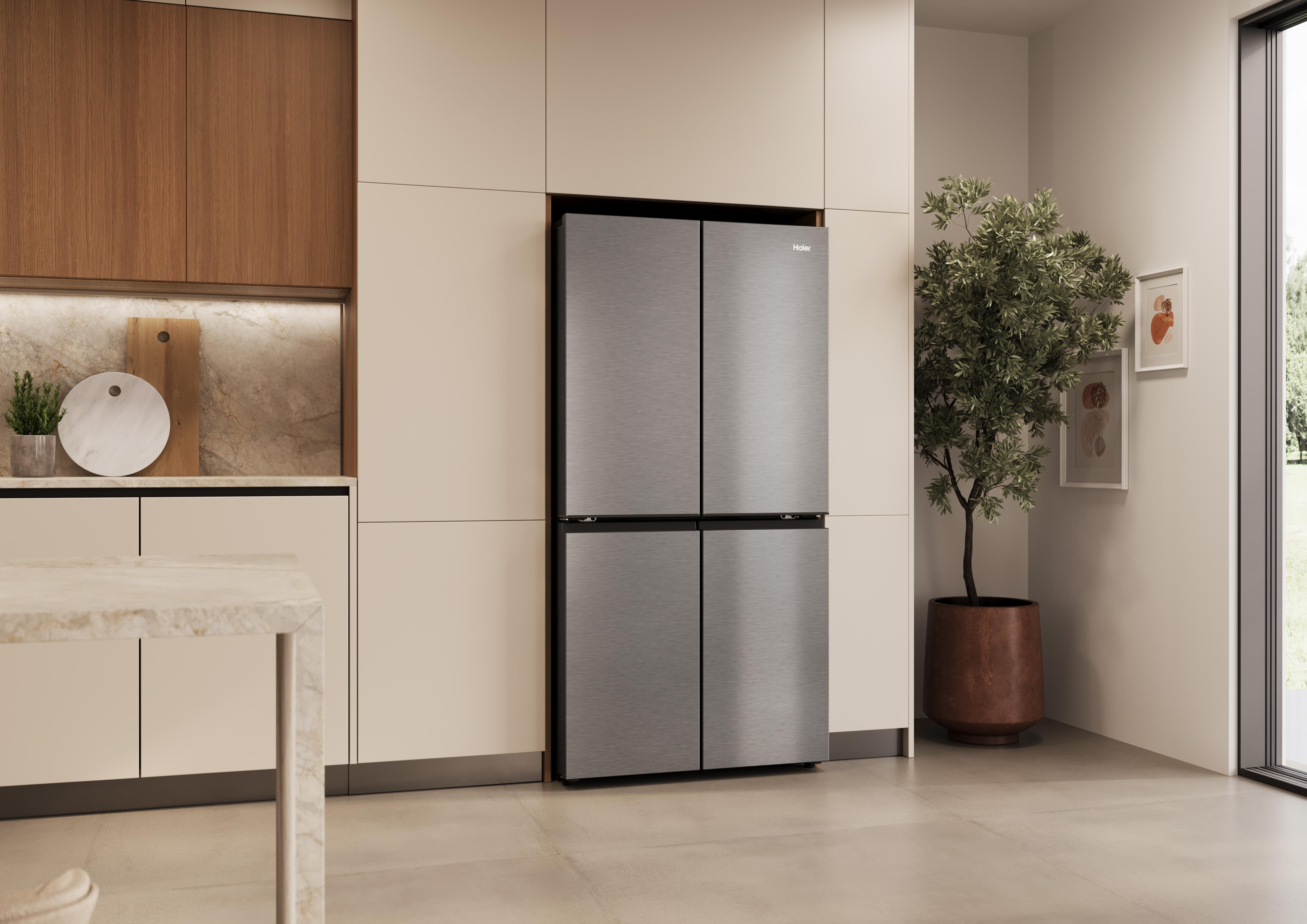 Refrigerador moderno de acero inoxidable junto a un árbol en maceta.