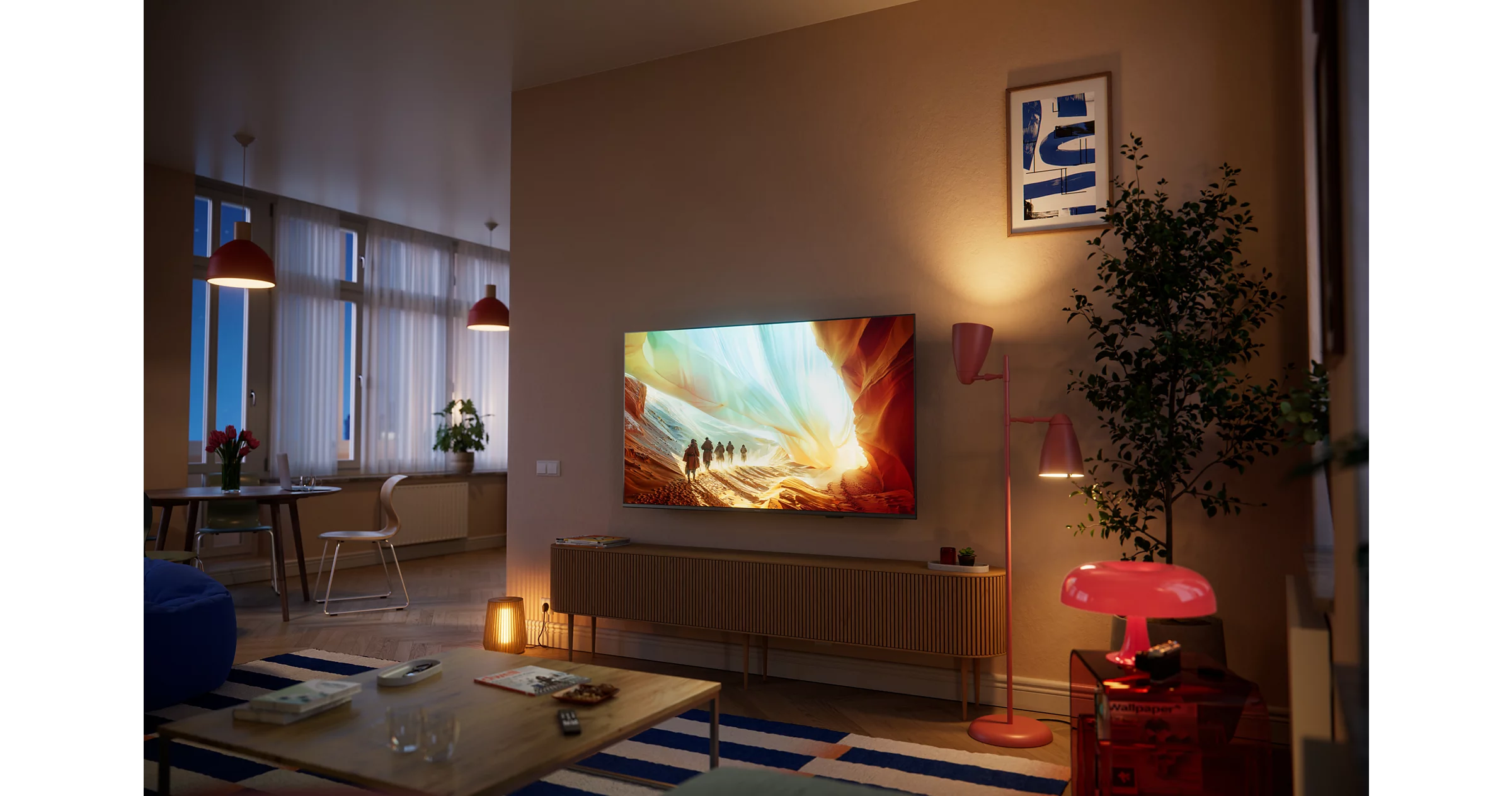 Ein Wohnzimmer mit Sofa, Couchtisch, Fernseher, Pflanzen und Lampen.