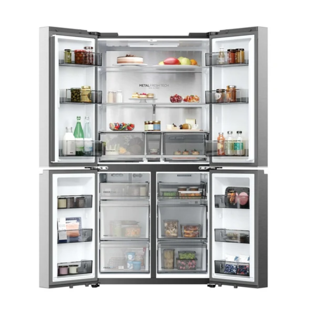 Refrigerador plateado abierto con comida en estantes: pasteles, frutas, verduras, bebidas, frascos.