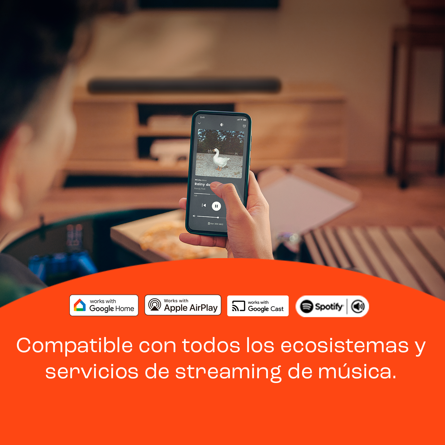 Una mano sostiene un smartphone con imagen de ganso y controles musicales. Logos de Google, Apple y Spotify.
