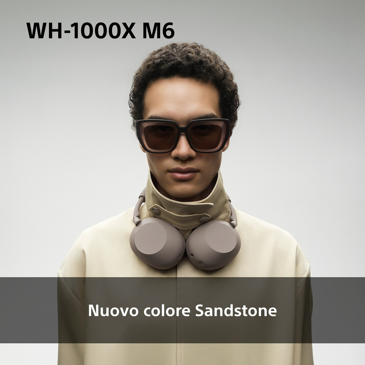 Uomo con cuffie e occhiali da sole, con indosso una giacca color cachi.