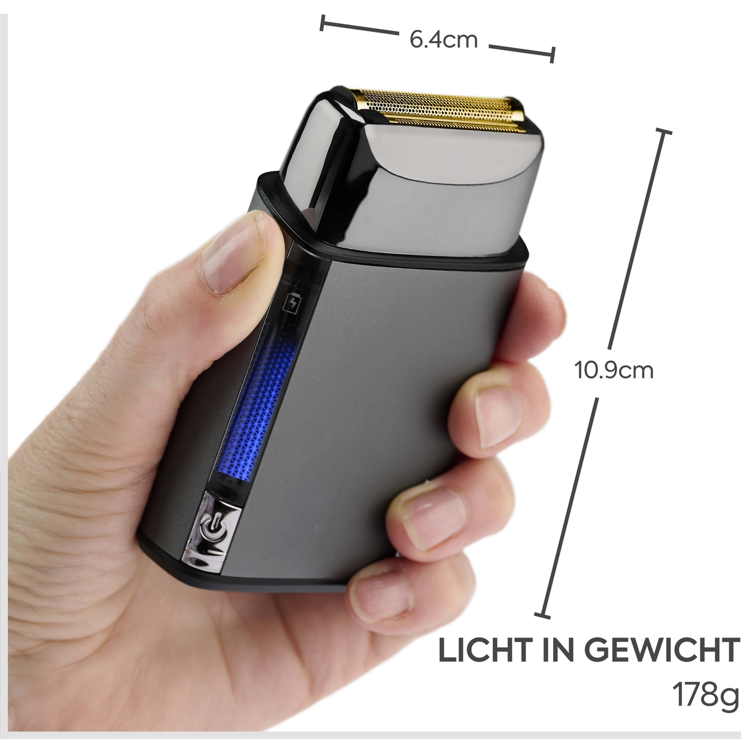 Een hand houdt een kleine, grijze elektrische scheerapparaat met gouden mesjes vast.