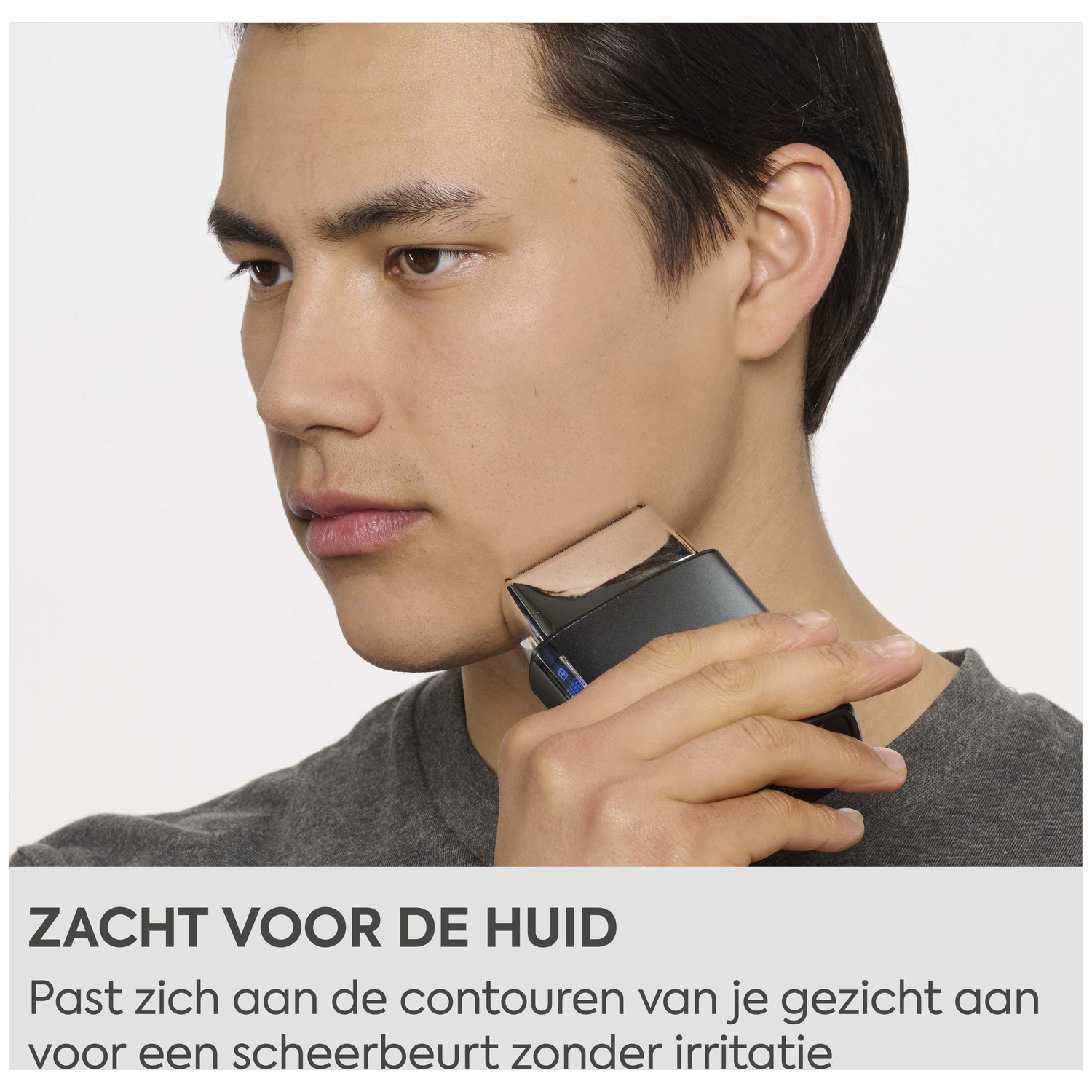 A man shaves his face with a black shaver that contours to his skin.