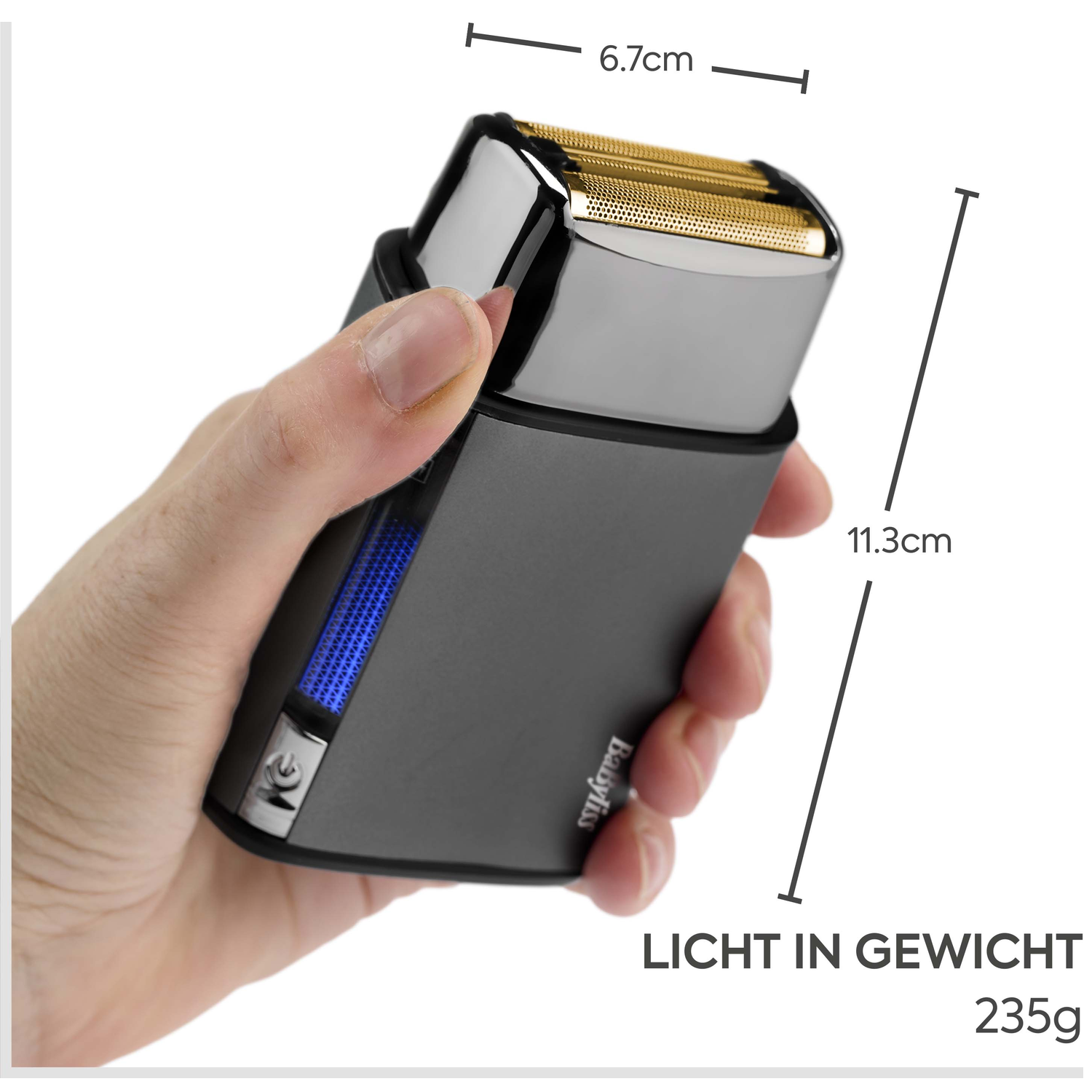 A hand holds a dark travel shaver with a gold foil head. Dimensions are shown.