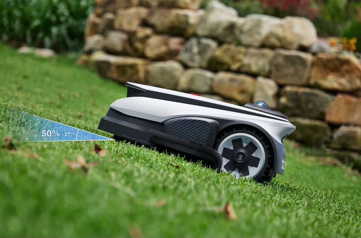 Ein Mähroboter mit einem Neigungsmesser in einer grünen Rasenlandschaft.