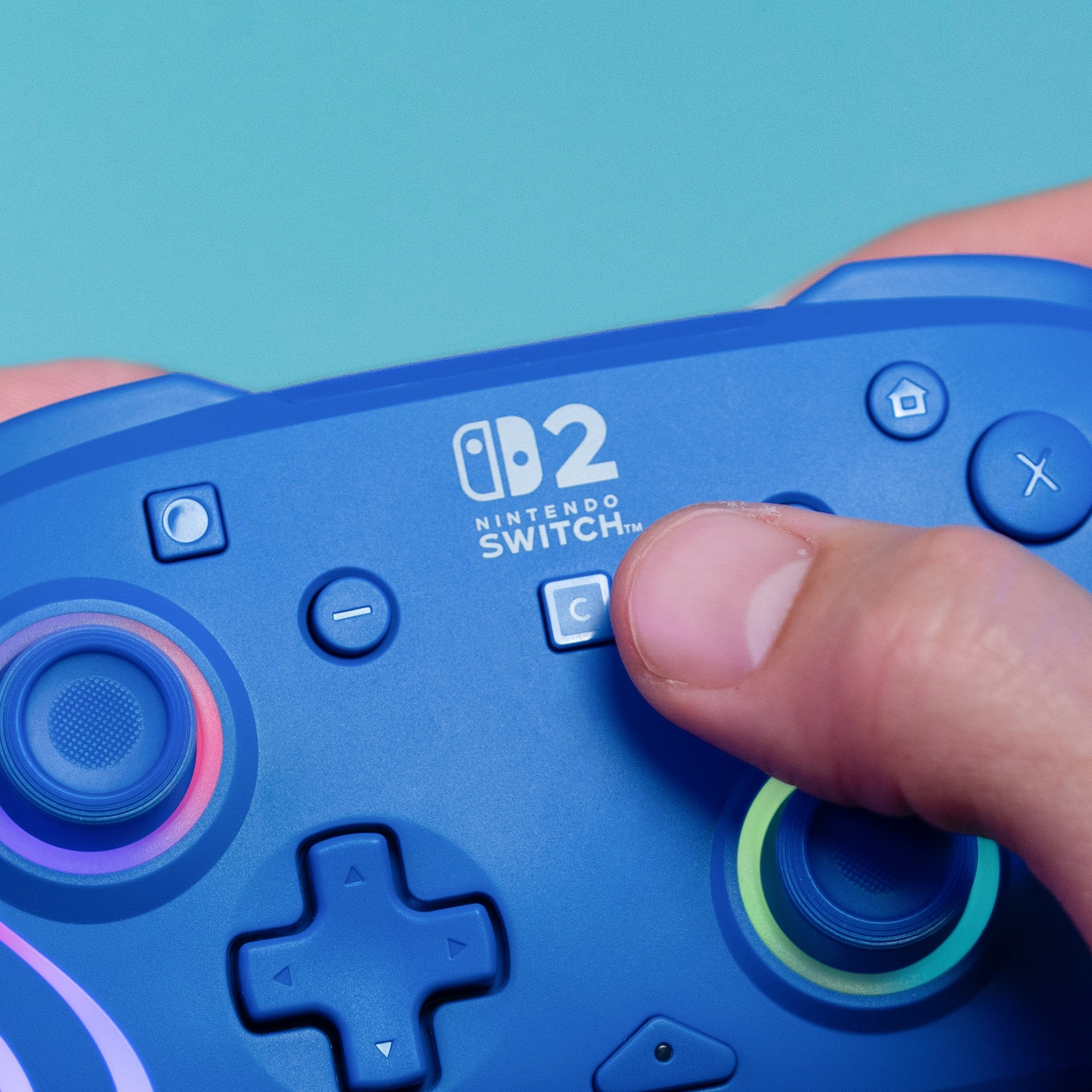 Manette bleue Nintendo Switch 2 avec pouce sur le stick droit, lumières vives.