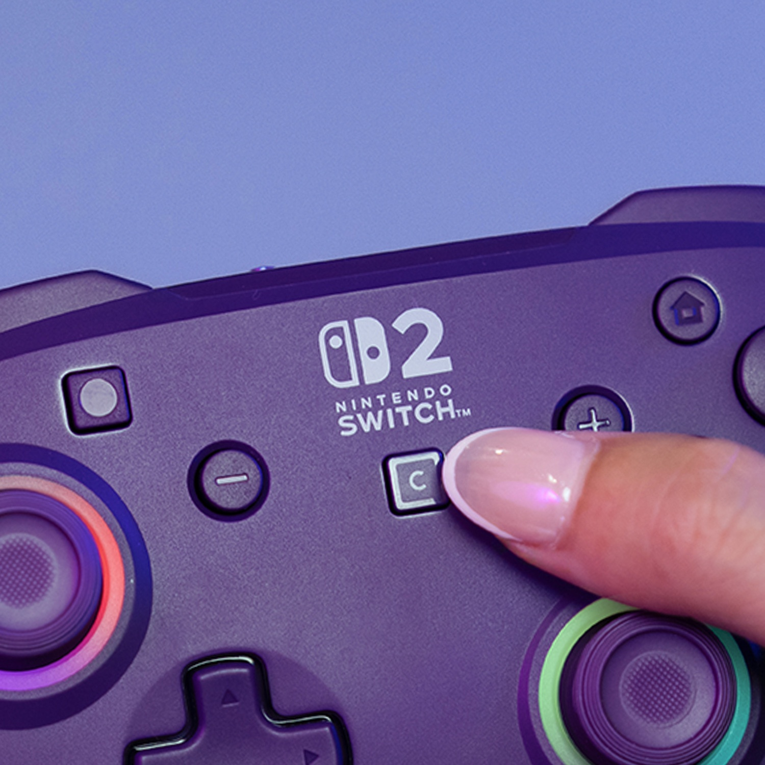 Une main appuie sur le bouton C d'une manette violette Nintendo Switch.