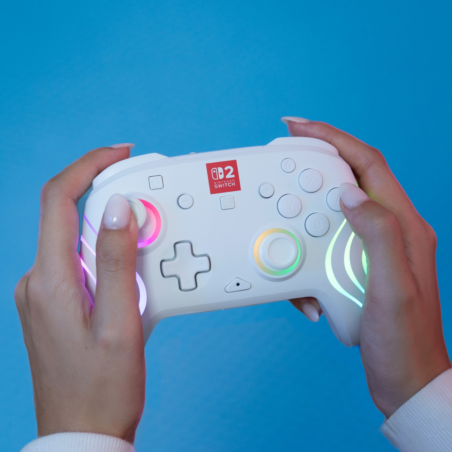 Manette blanche Nintendo Switch avec lumières colorées, tenue par des mains.
