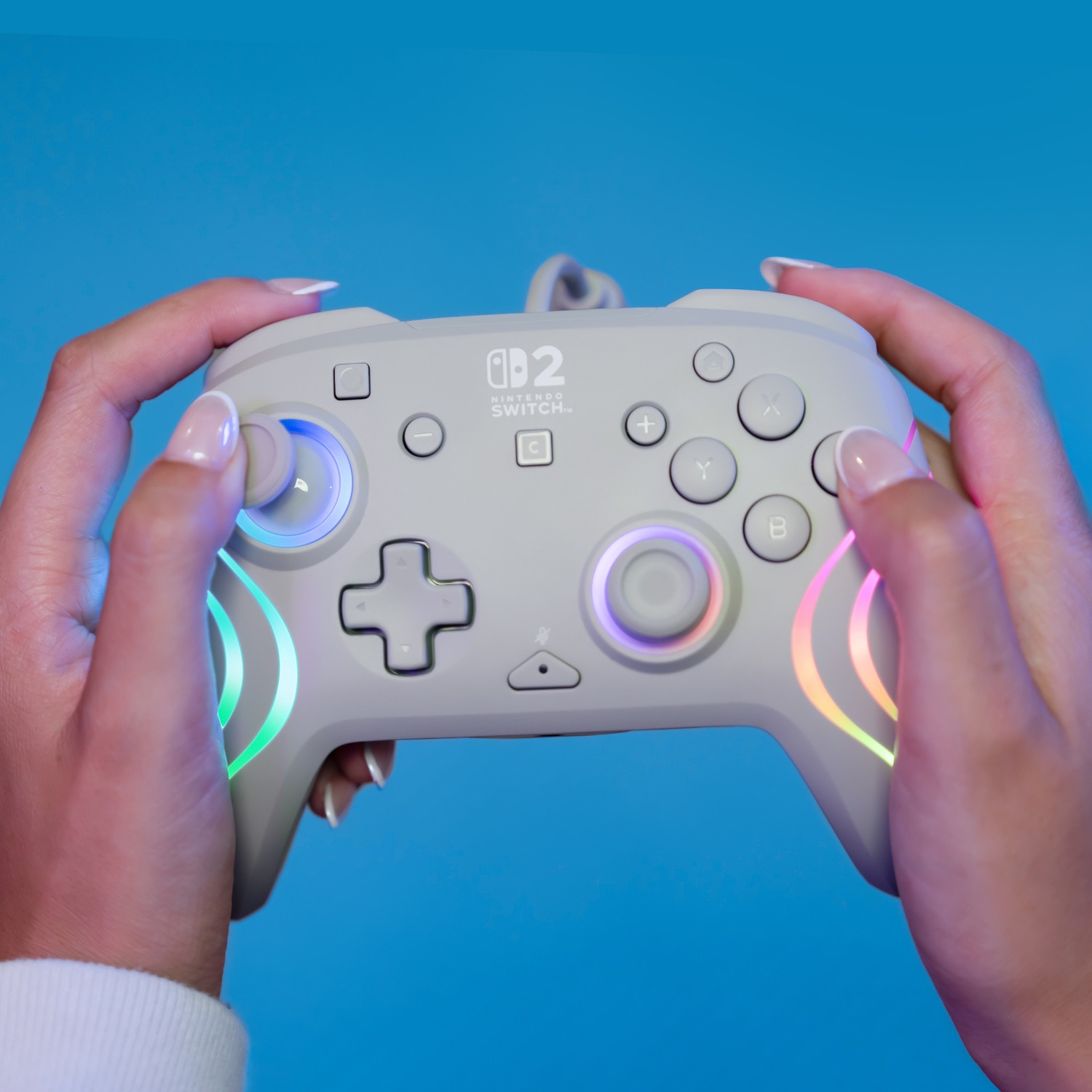 Manette grise Nintendo Switch avec anneaux lumineux, tenue par des mains.