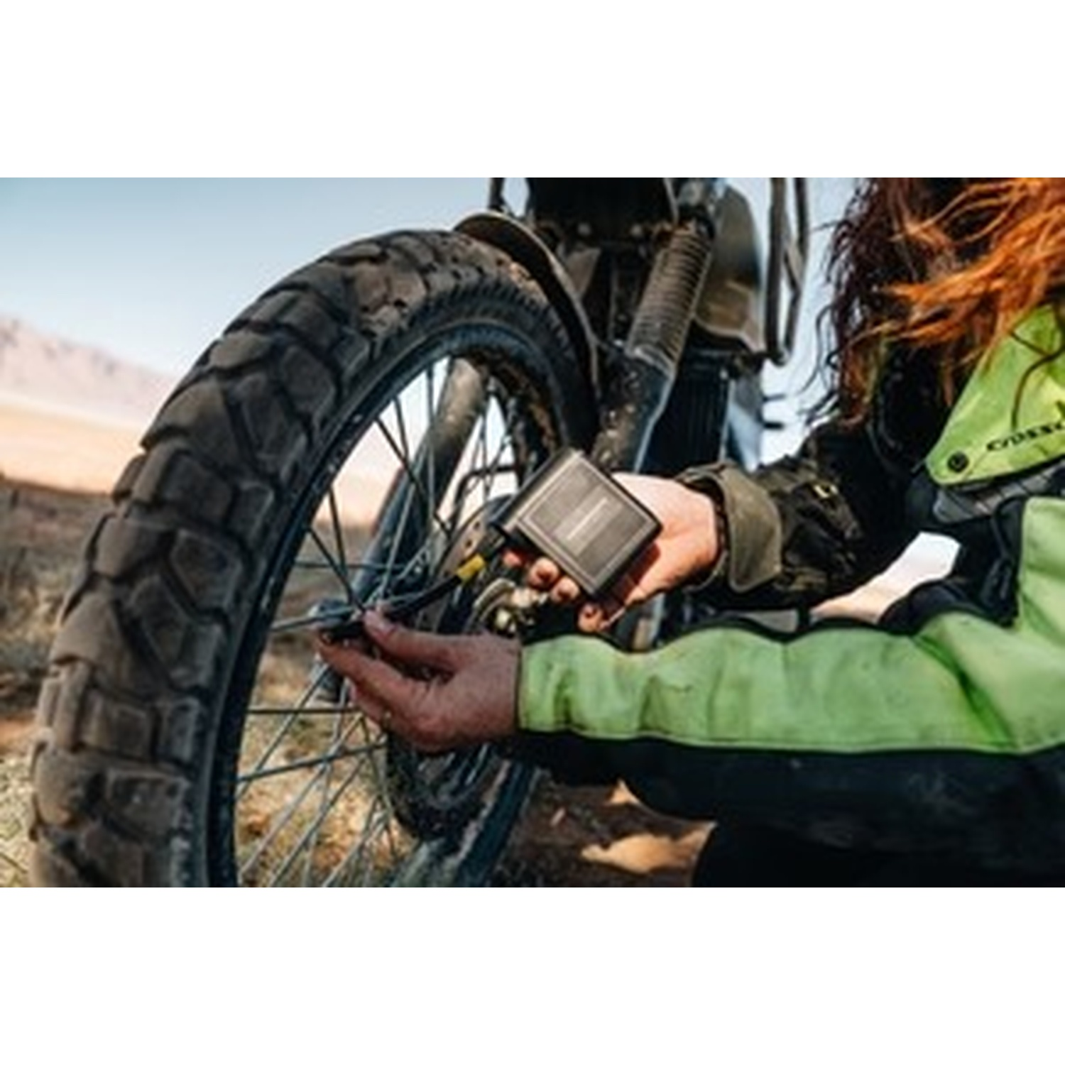 Una persona ripara uno pneumatico da moto all'aperto con uno strumento.