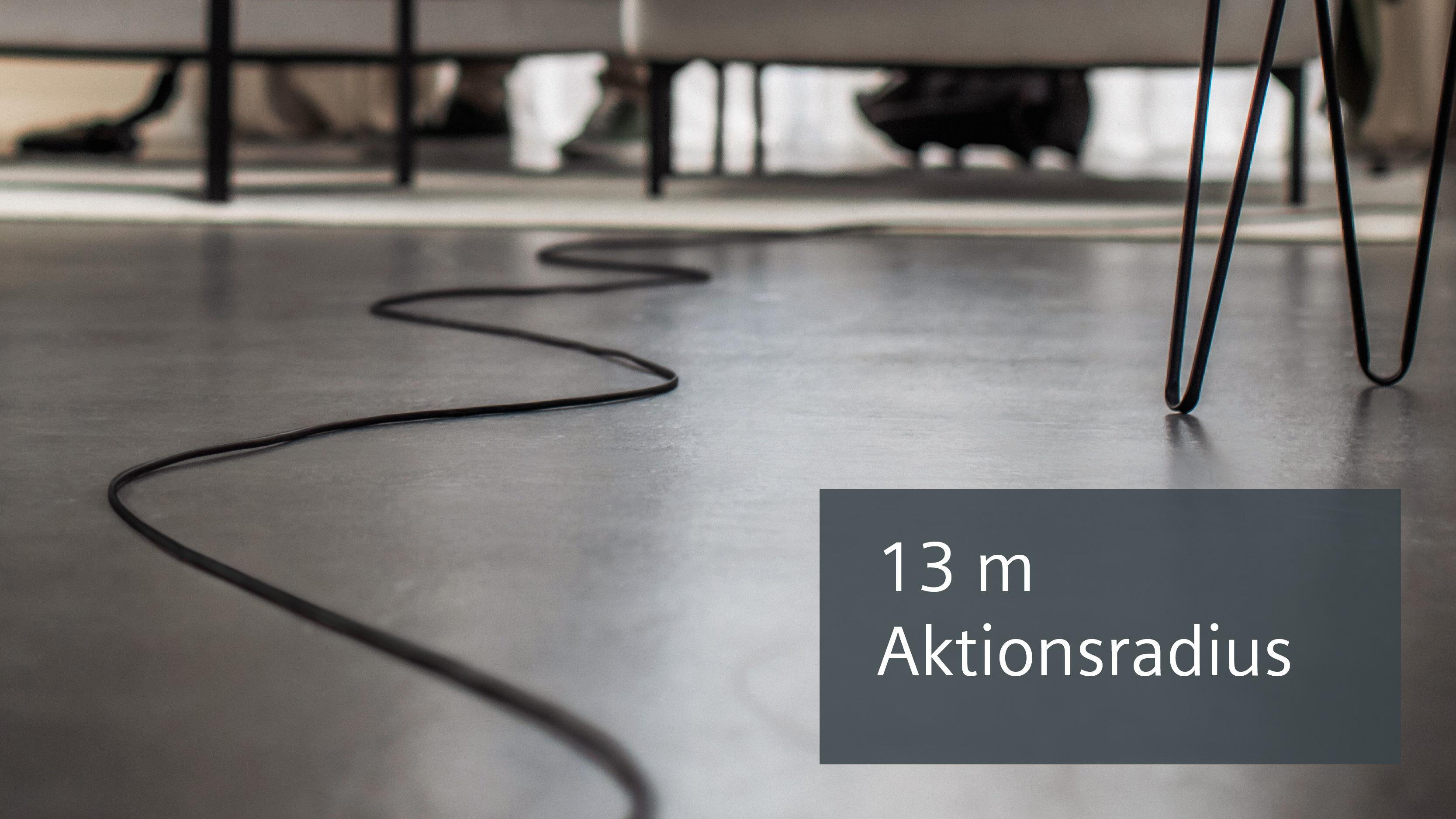 Schwarzes Kabel auf grauem Boden mit Text '13 m Aktionsradius'.