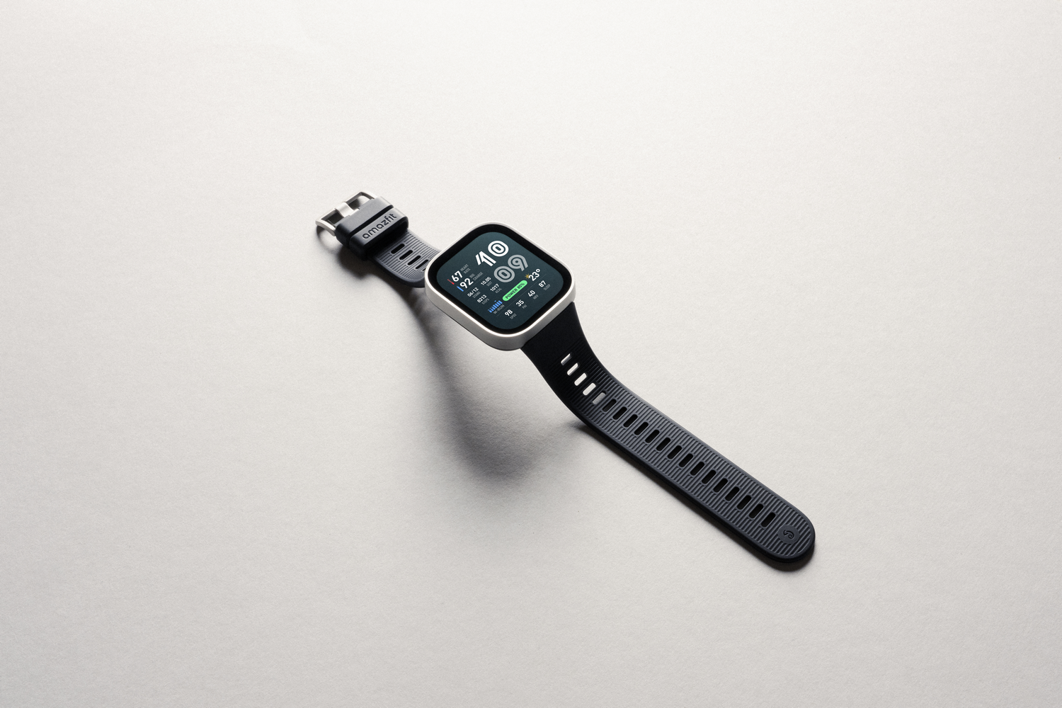 Un reloj inteligente negro con correa de silicona sobre fondo gris.