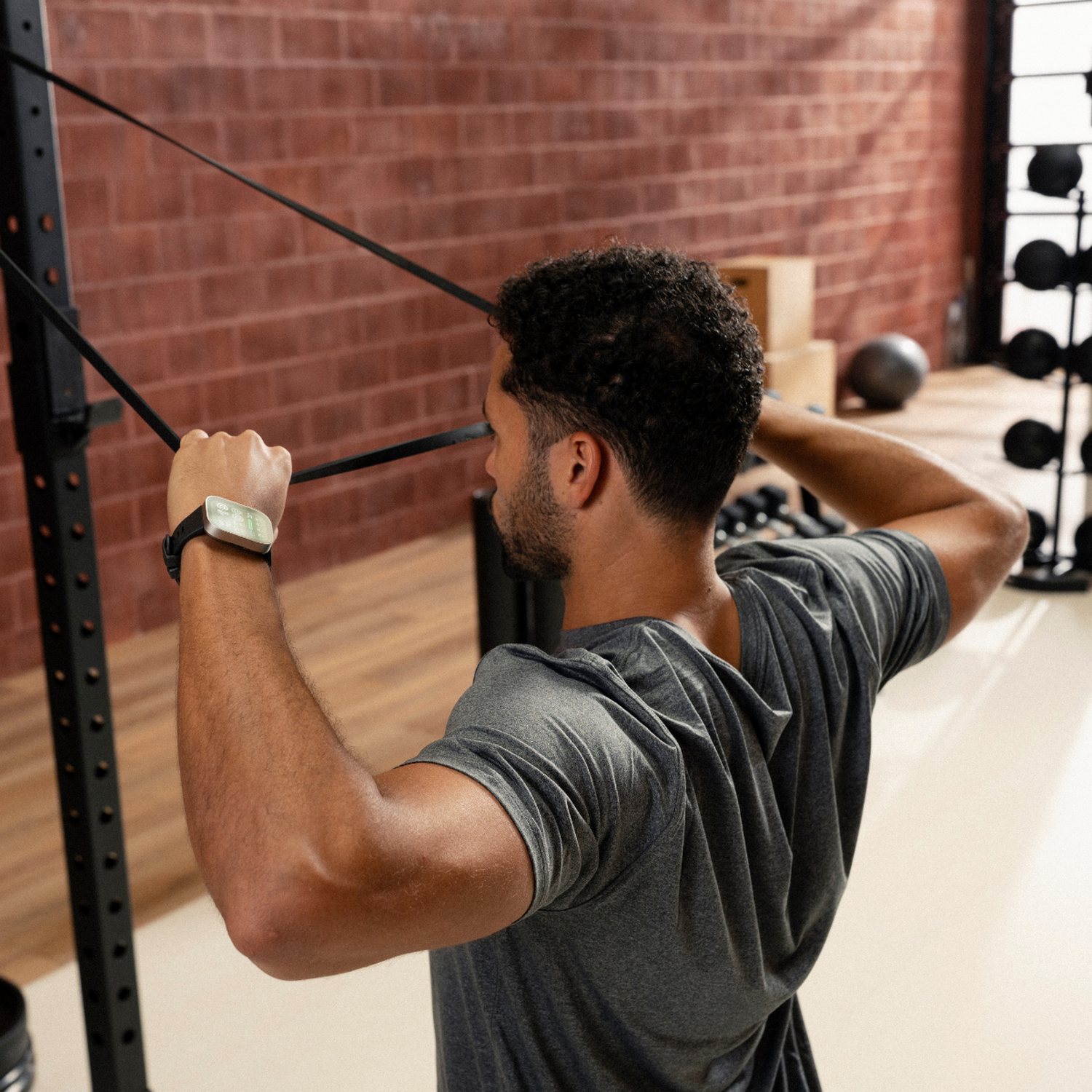 Hombre haciendo ejercicio con bandas elásticas unidas a un rack en un gimnasio.