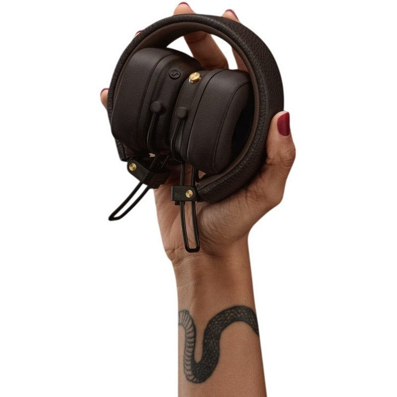 Auriculares marrones sostenidos por una mano con tatuaje de serpiente.