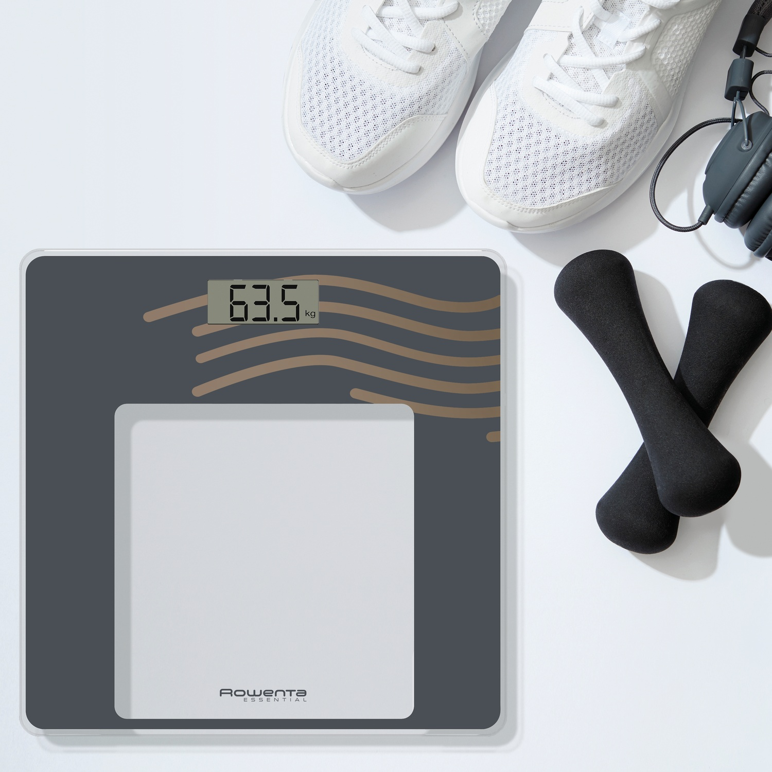 Digitale weegschaal met koptelefoon, sneakers en dumbbells.
