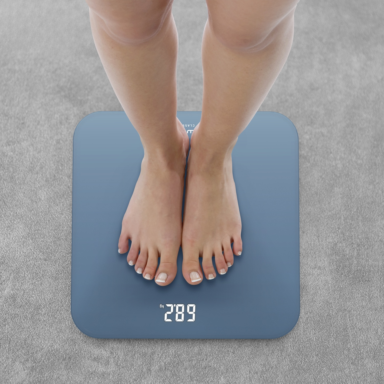 Pieds sur une balance bleue affichant 289 kg.