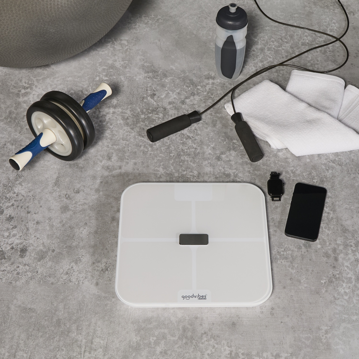 Fitnessapparatuur: buikroller, springtouw, waterfles, weegschaal, telefoon en horloge.