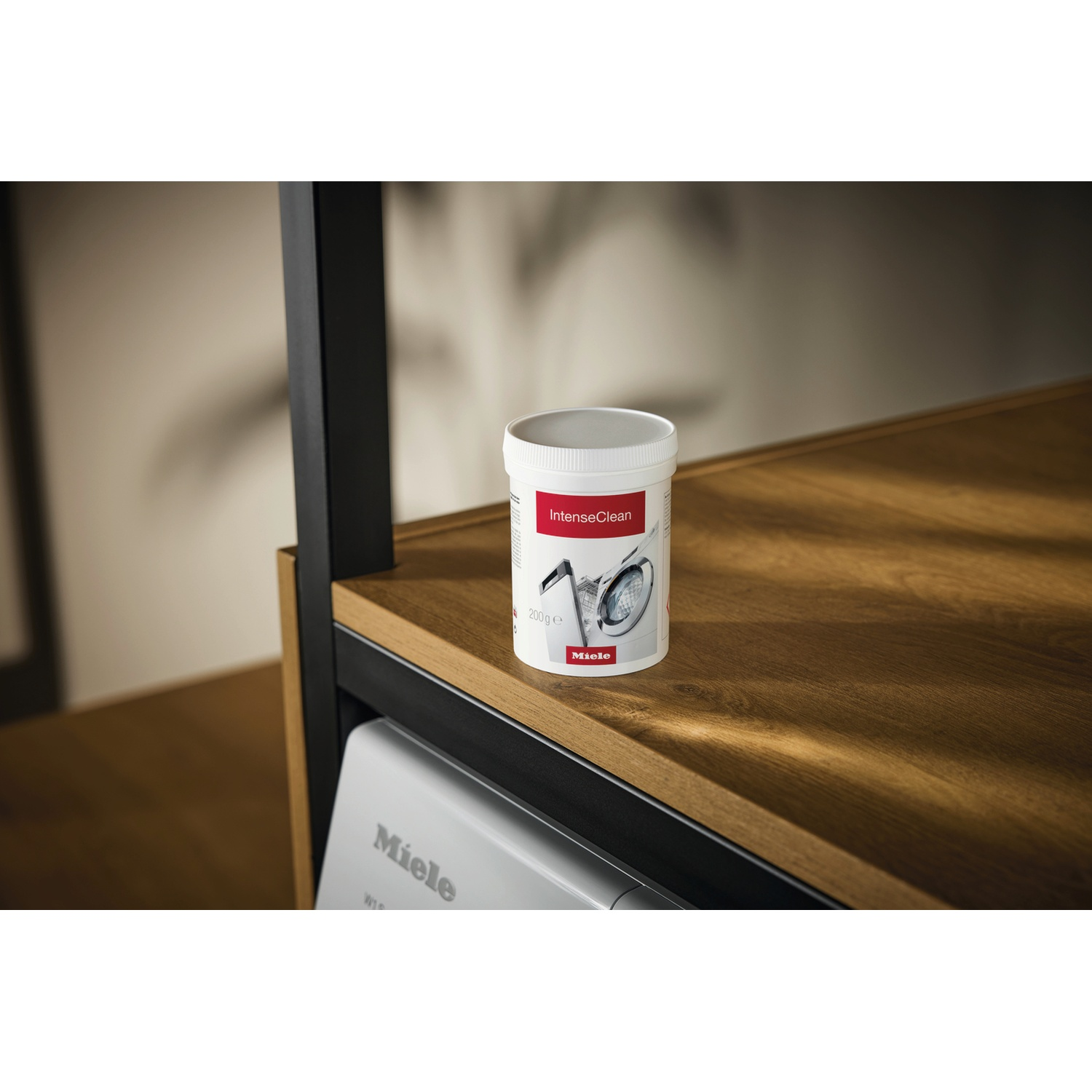 Een witte container met het label IntenseClean en een afbeelding van een wasmachine staat op een houten plank.