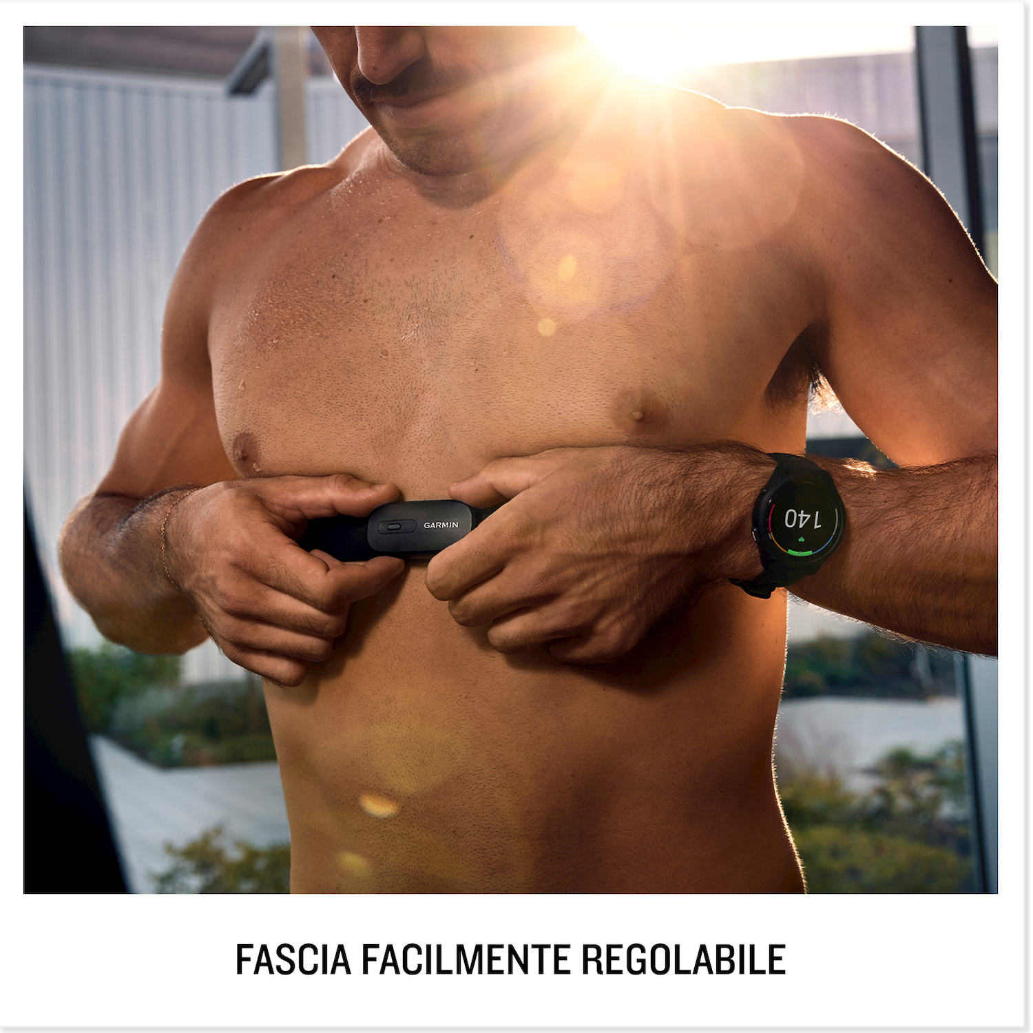 Un uomo fissa un cardiofrequenzimetro nero al busto. Un orologio smart è visibile al polso.