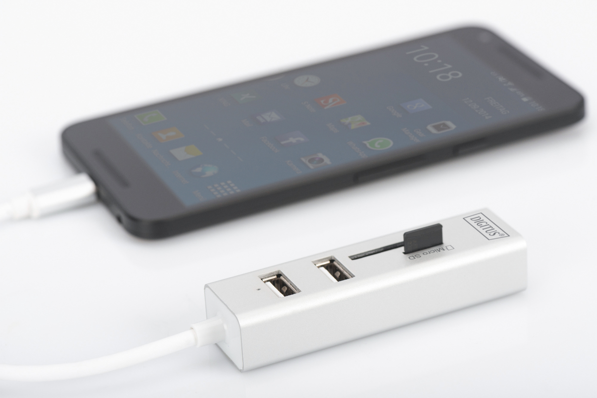 Ein Smartphone ist über ein USB-Kabel mit einem silbernen USB-Hub verbunden.