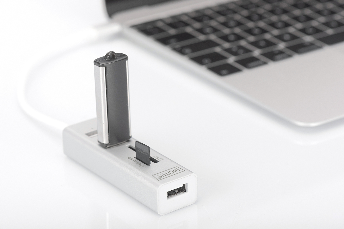 Ein silberner USB-Hub mit eingestecktem USB-Stick und SD-Karte, neben einem Laptop.
