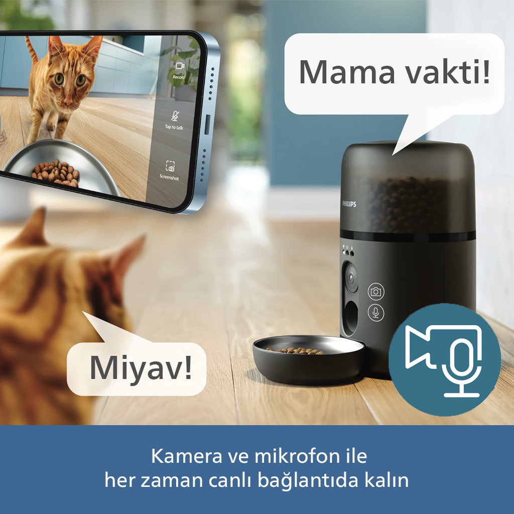 Bir iPhone mama kabının yanında bir kedi gösteriyor. Yanında bir evcil hayvan mama otomatı var.