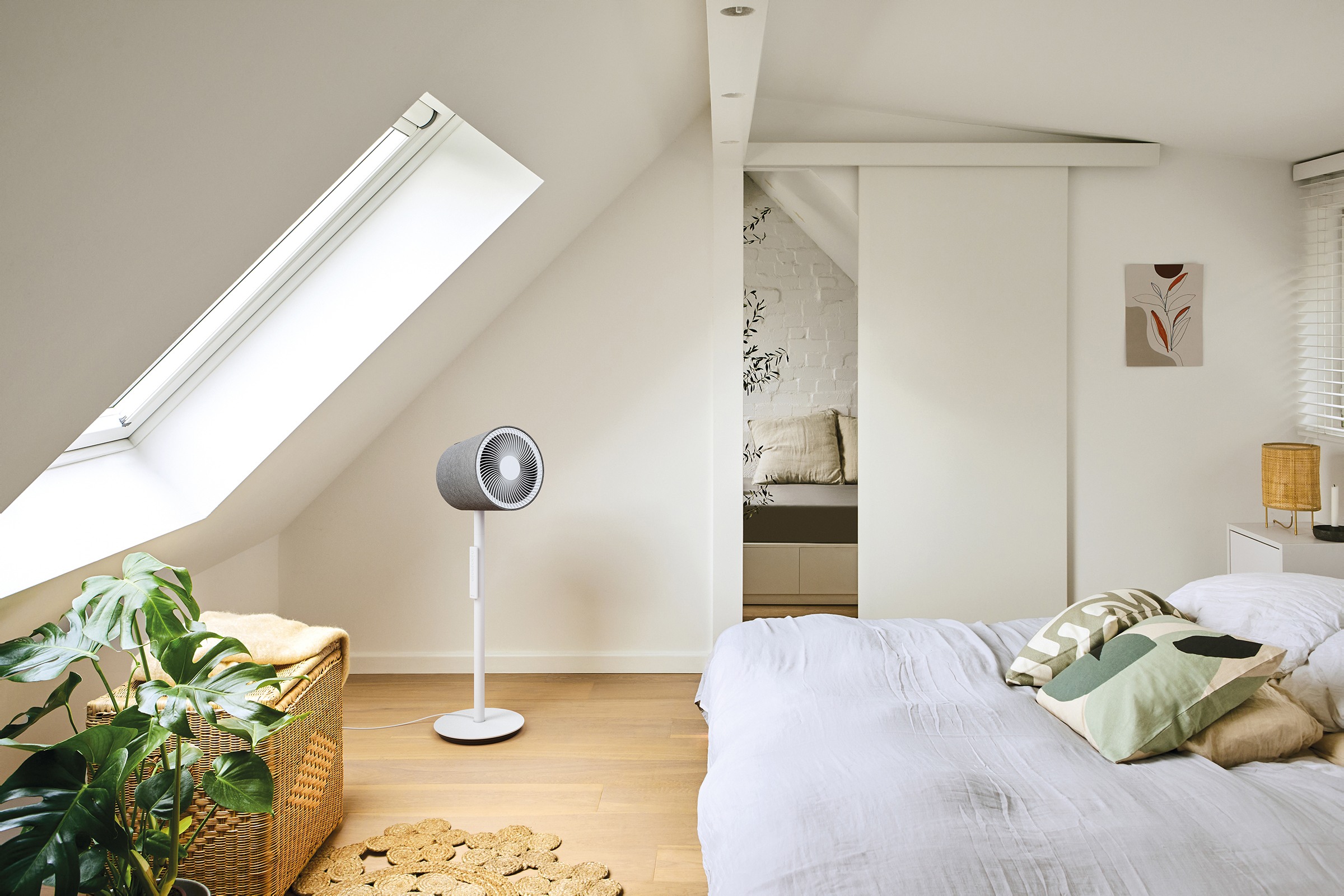 Ein Schlafzimmer mit Dachschräge, Bett, Ventilator und Pflanzen.