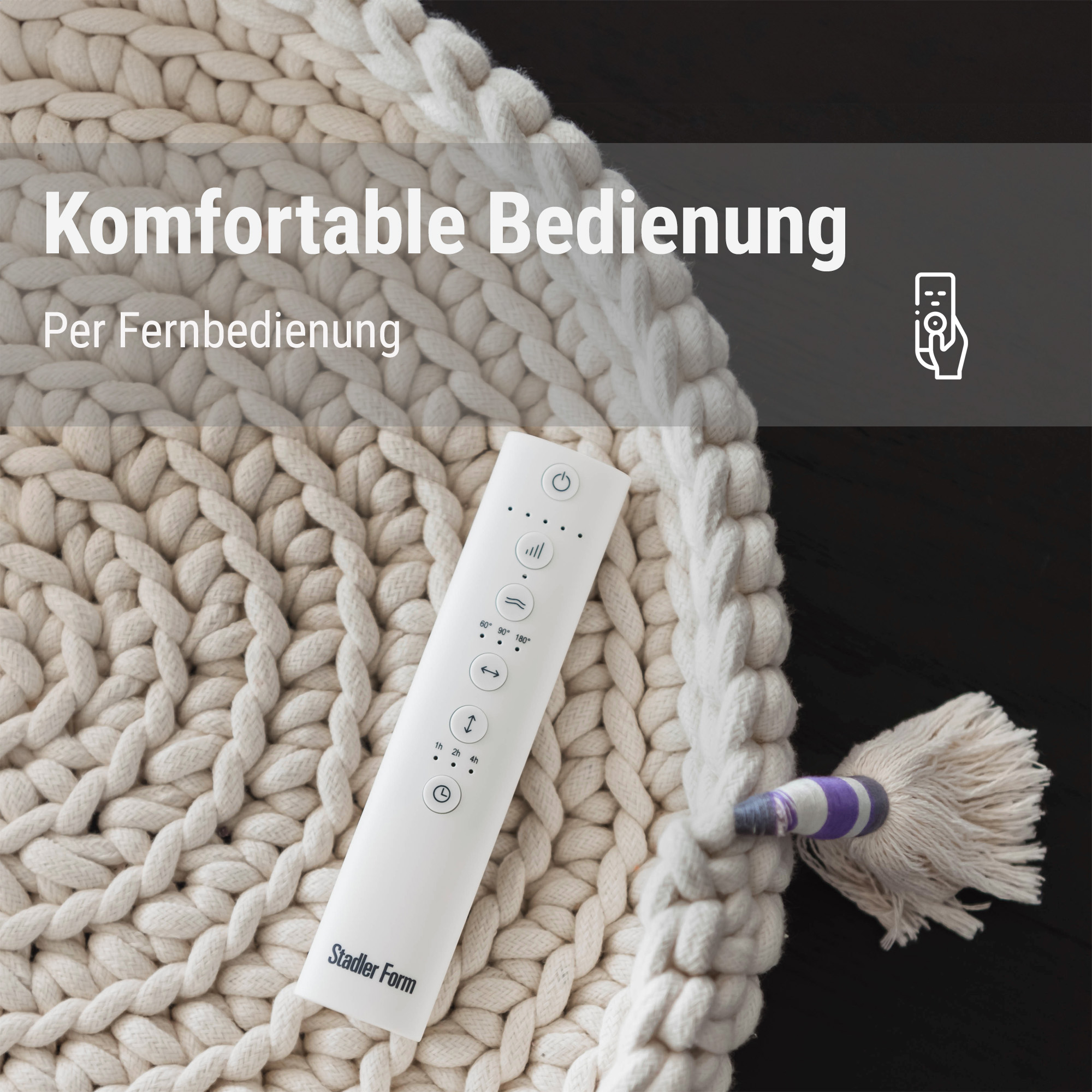 Ein weißes Fernbedienung-Gerät liegt auf einem dicken, cremefarbenen Strickstoff.