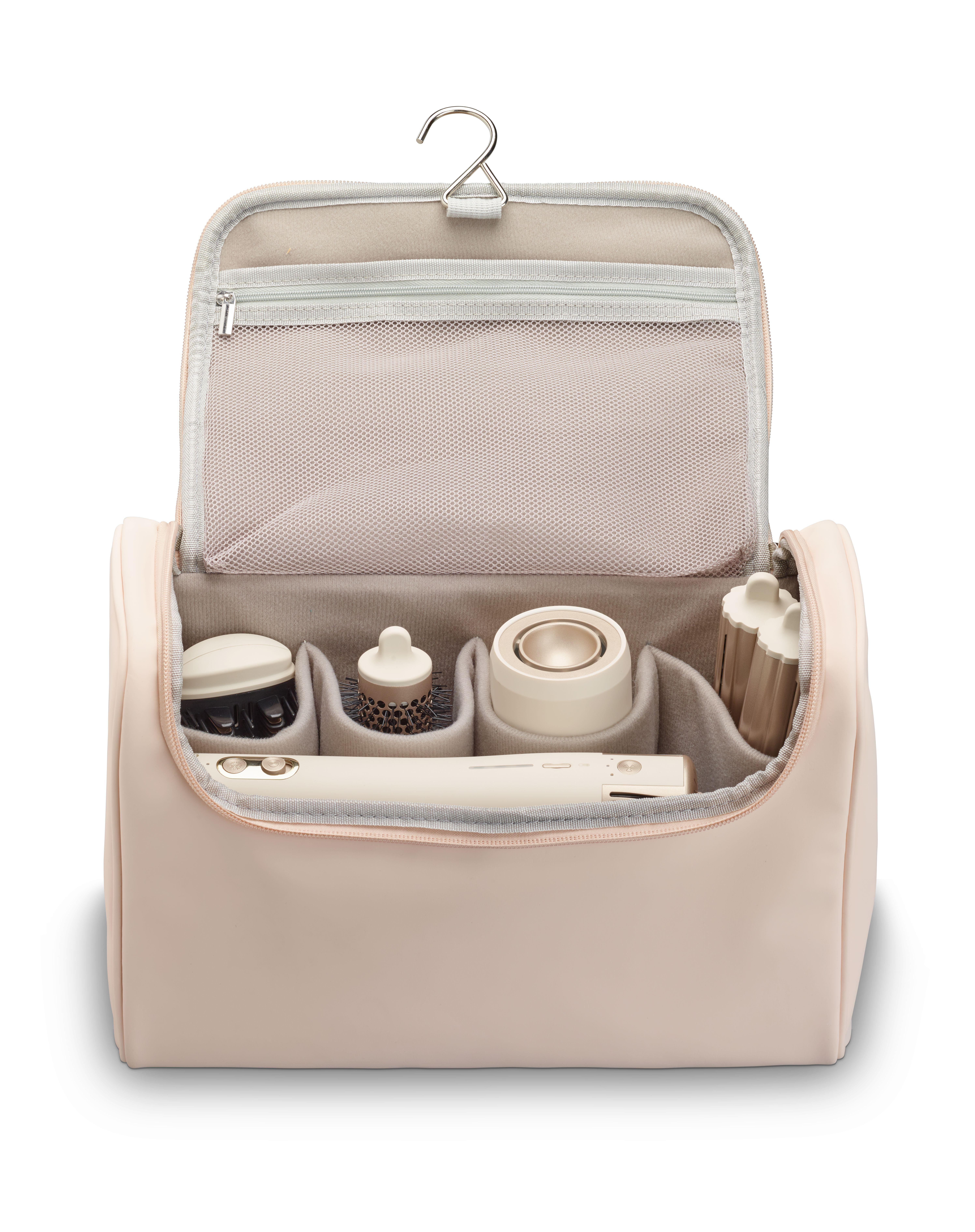 Eine offene rosafarbene Kosmetiktasche mit Haarpflegegeräten und Zubehör.