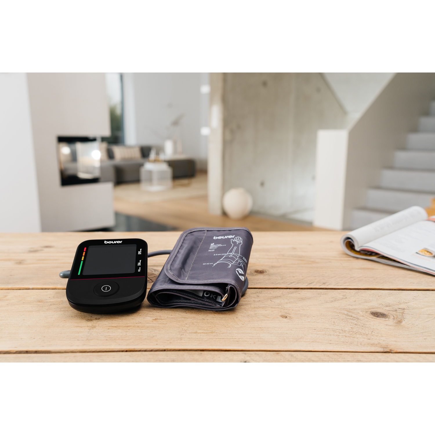 A black digital blood pressure monitor and cuff rest on a wooden table.
