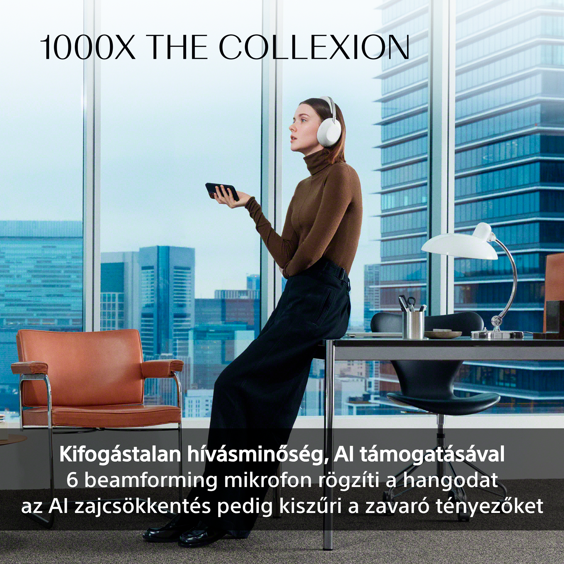 Egy fejhallgatót viselő nő okostelefont tart egy irodában, városra néző kilátással.
