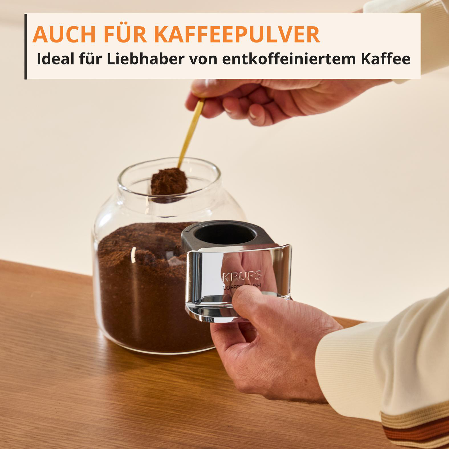 Ein Löffel mit Kaffeepulver wird aus einem Glasbehälter genommen.