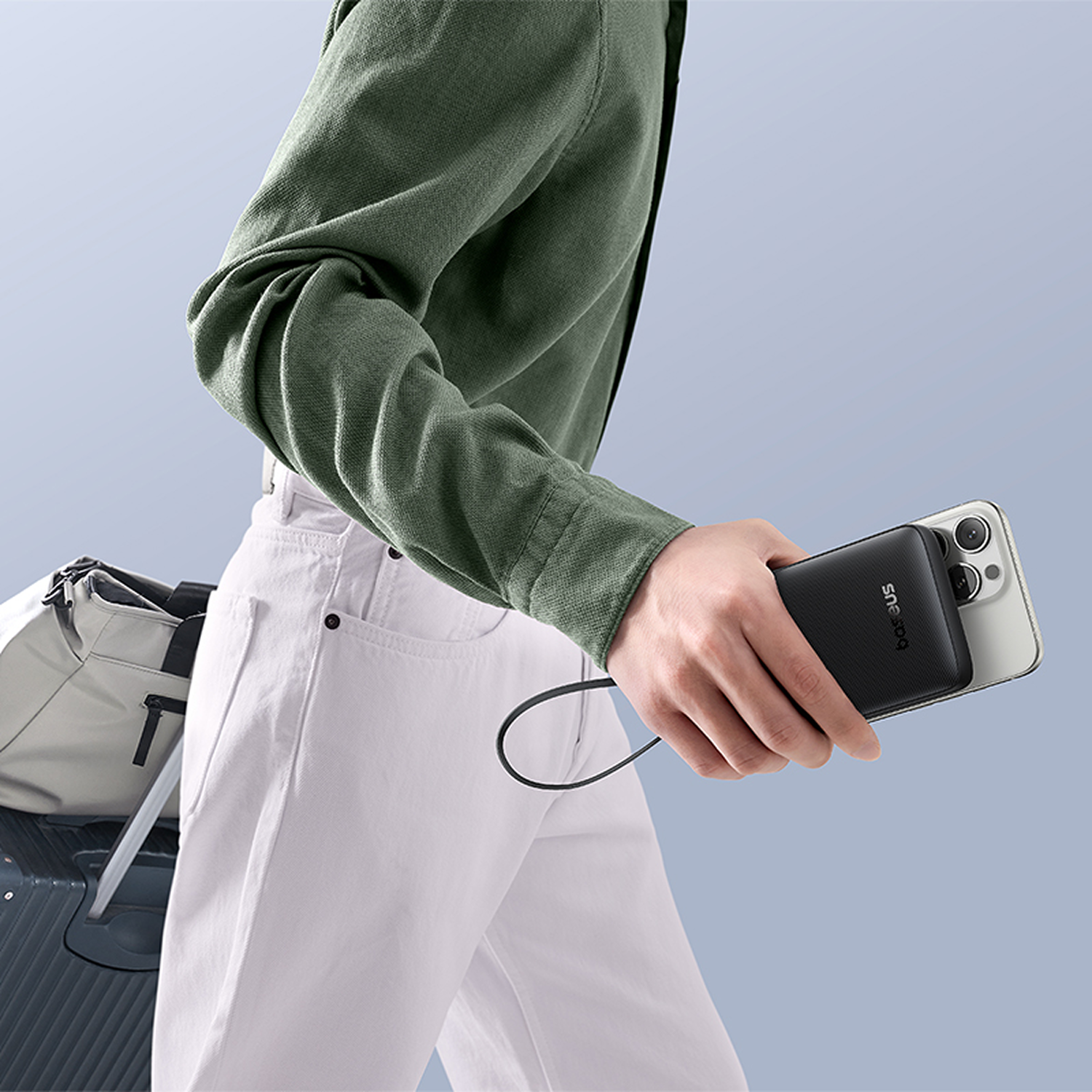 Persona con pantalones blancos y camisa verde sostiene un cargador negro.