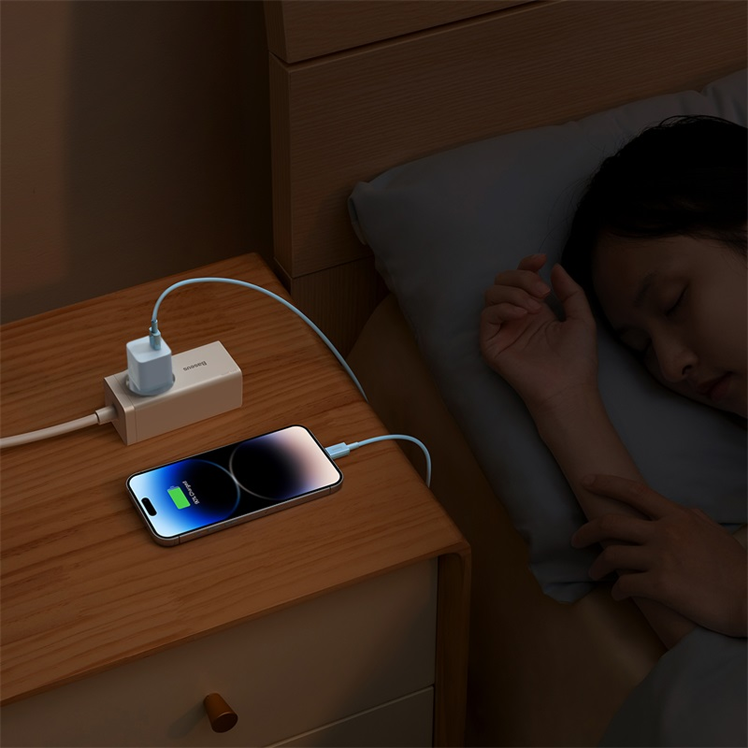Un teléfono se carga en una mesita de noche junto a una persona durmiendo.