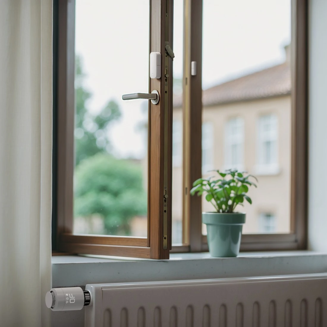 Ein Thermostat am Heizkörper vor einem offenen Fenster mit einer Pflanze.