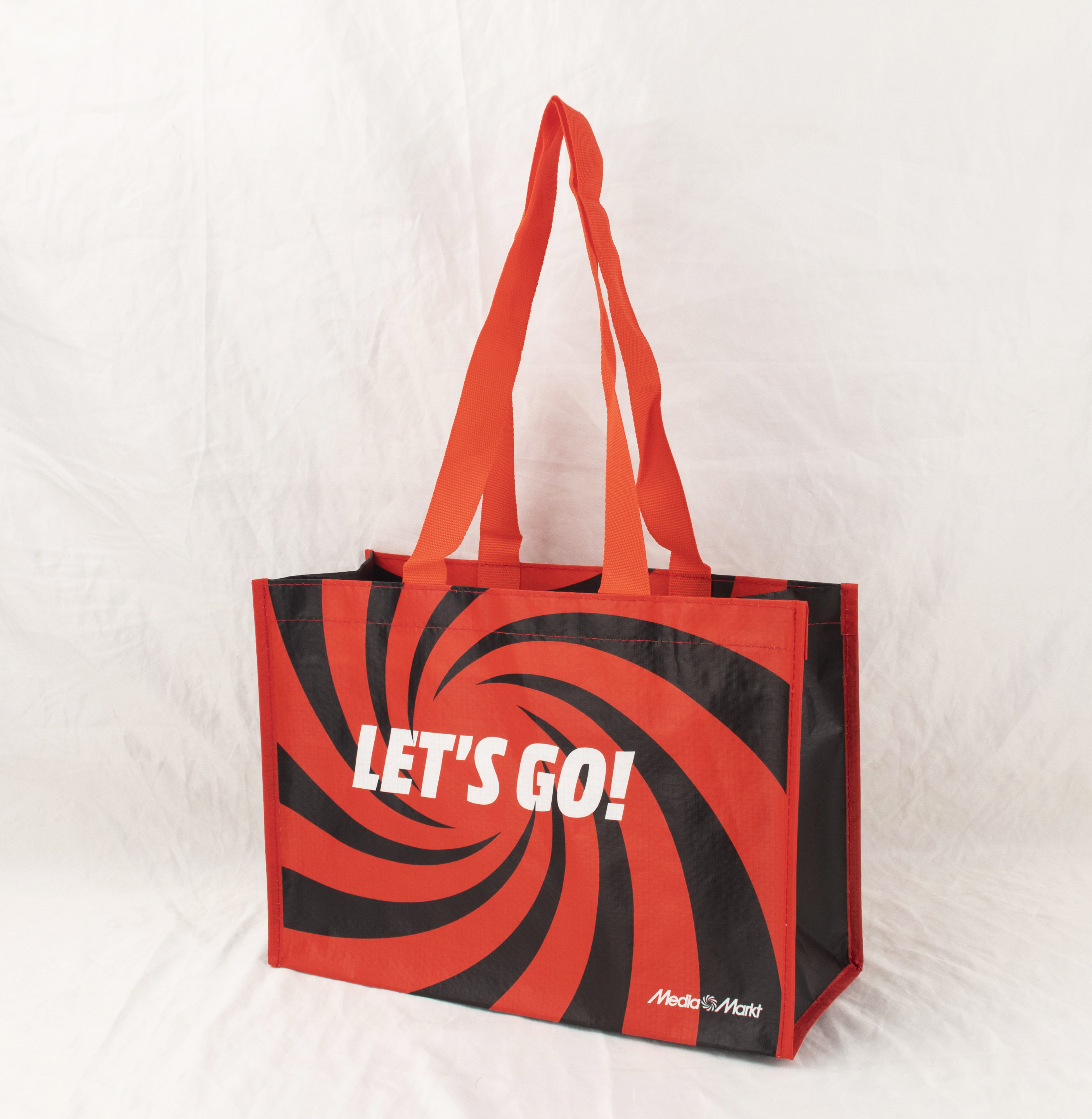 Rote und schwarze Einkaufstasche mit "LET'S GO!"-Aufschrift und Mediamarkt-Logo.
