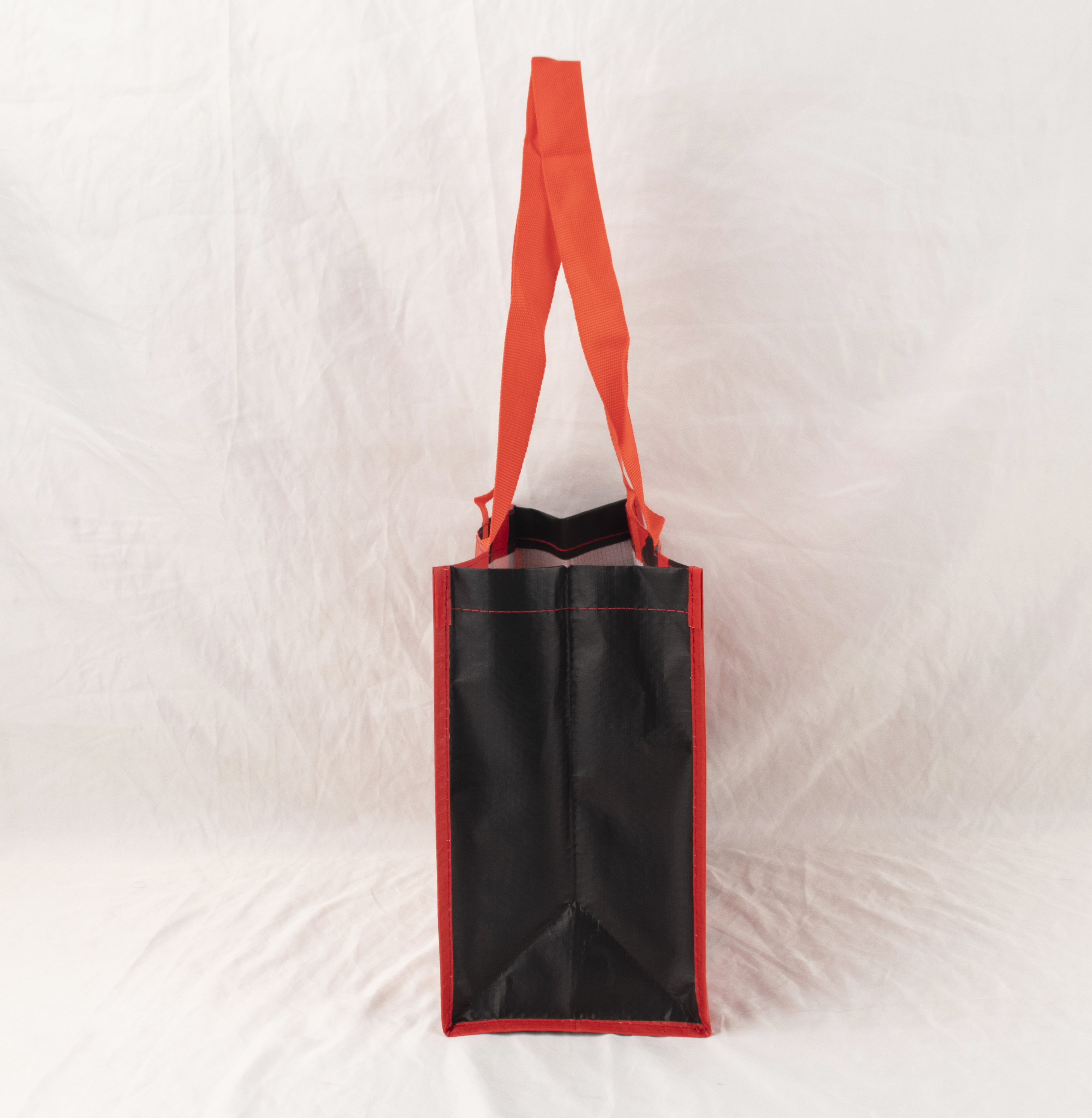 Schwarze Tasche mit roten Rändern und Henkeln auf weißem Hintergrund.