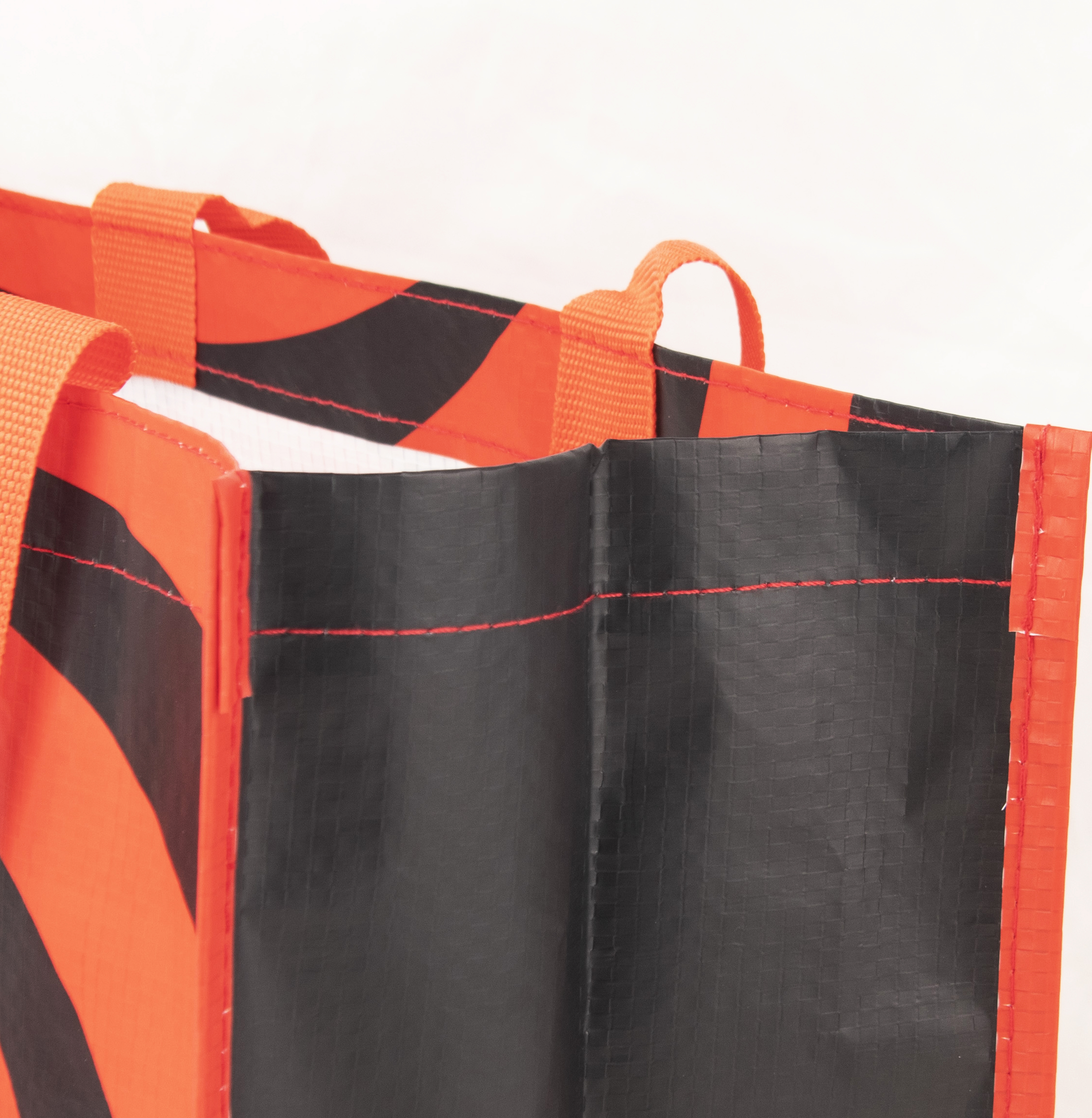 Tragetasche mit orange-schwarzem Muster und Henkeln.