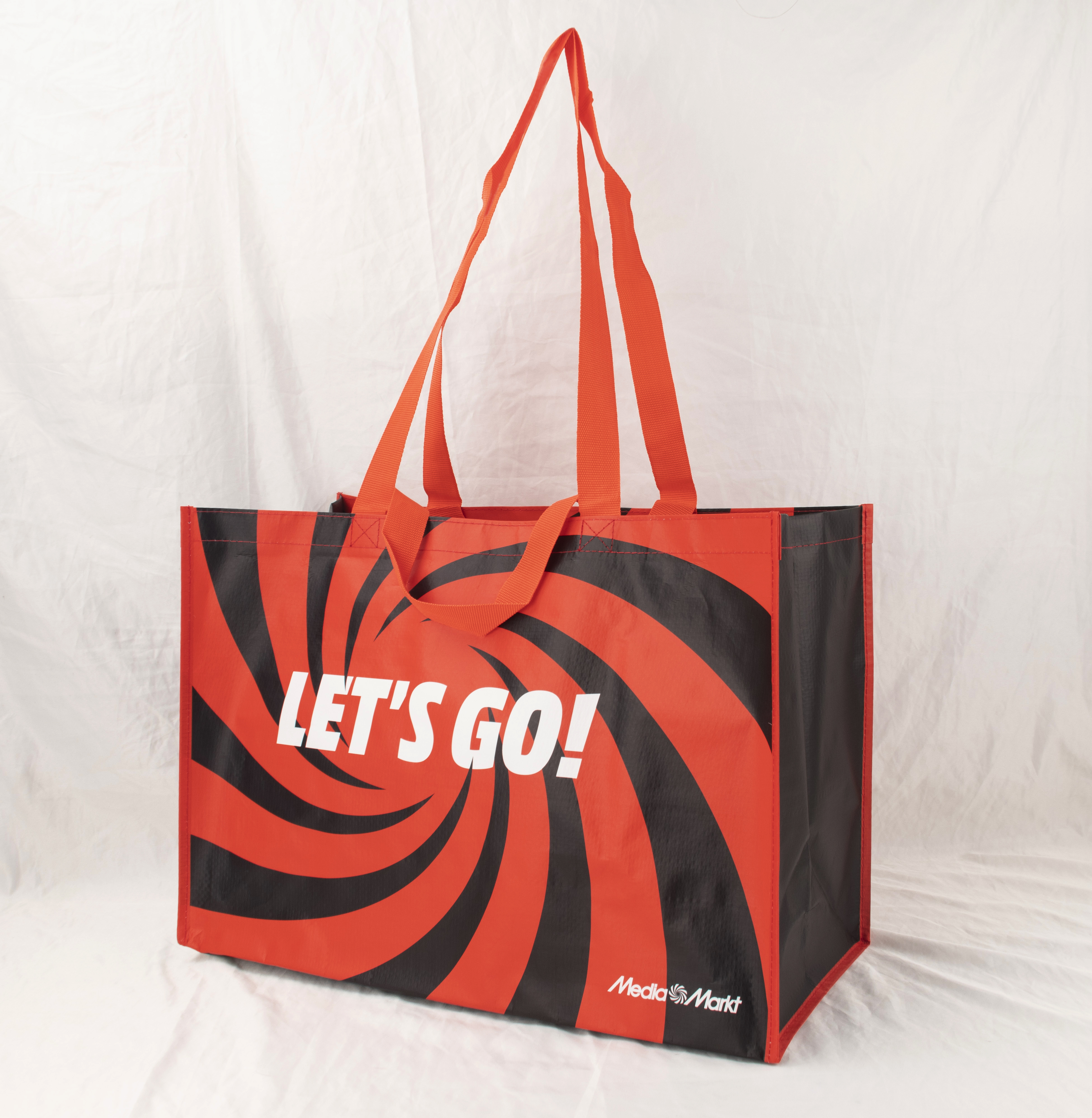 Rote und schwarze Einkaufstasche mit „LET'S GO!“ und MediaMarkt-Logo.