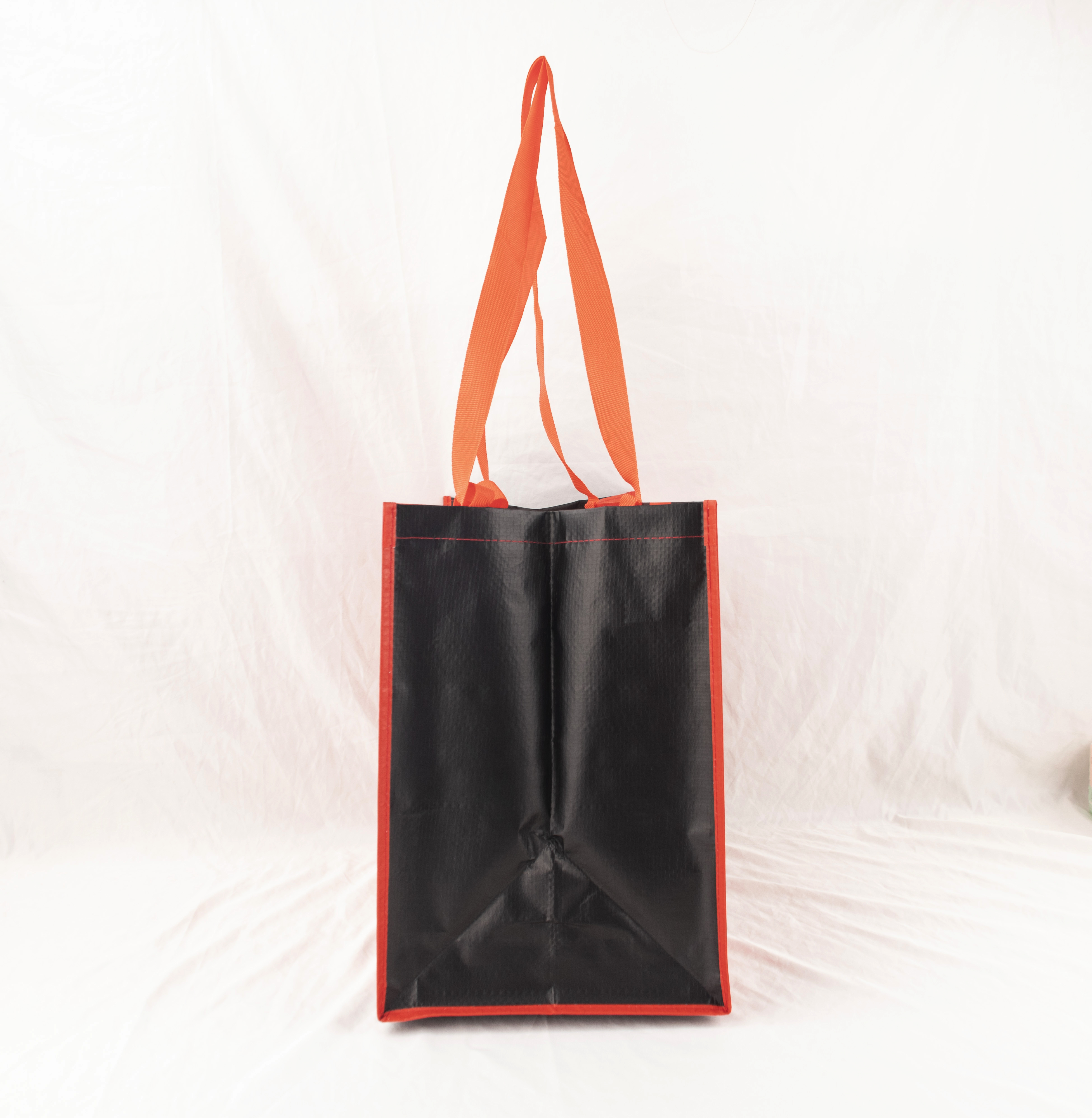 Schwarze Tasche mit roten Kanten und orangefarbenen Henkeln.