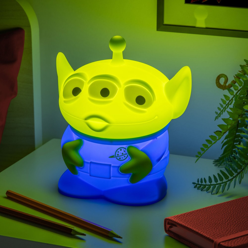 Una lámpara alienígena brillante con tres ojos, en azul y amarillo, sobre un escritorio.