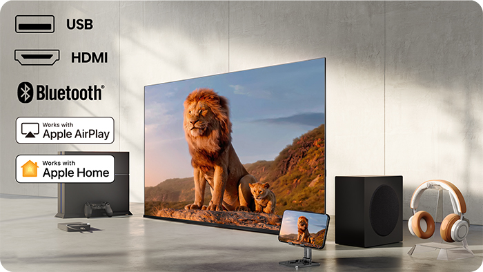 Nowoczesny telewizor z lwem i lwiątkiem. Obok subwoofer i słuchawki. Ikony USB, HDMI, Bluetooth.