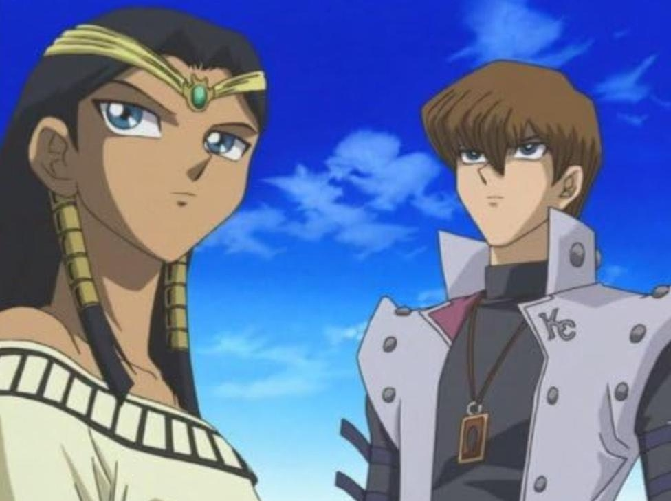 Zwei Anime-Charaktere, einer mit dunklem Haar und ägyptischer Kleidung, der andere mit braunem Haar im Anzug.