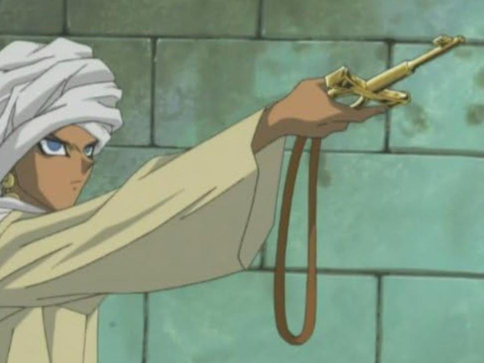 Mann mit weißem Turban und goldener Waffe vor einer Steinwand.