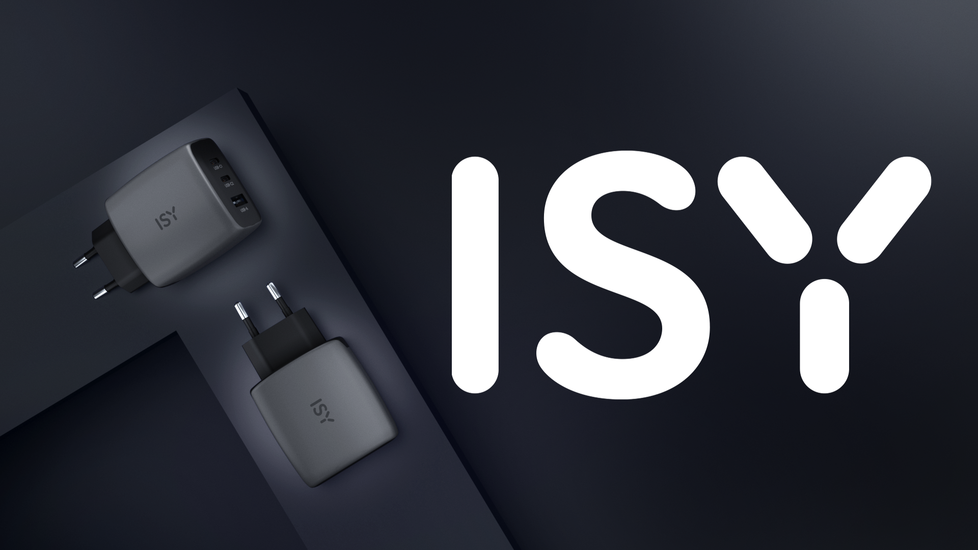 Dwa szare ładowarki ISY z portami USB na ciemnym tle.