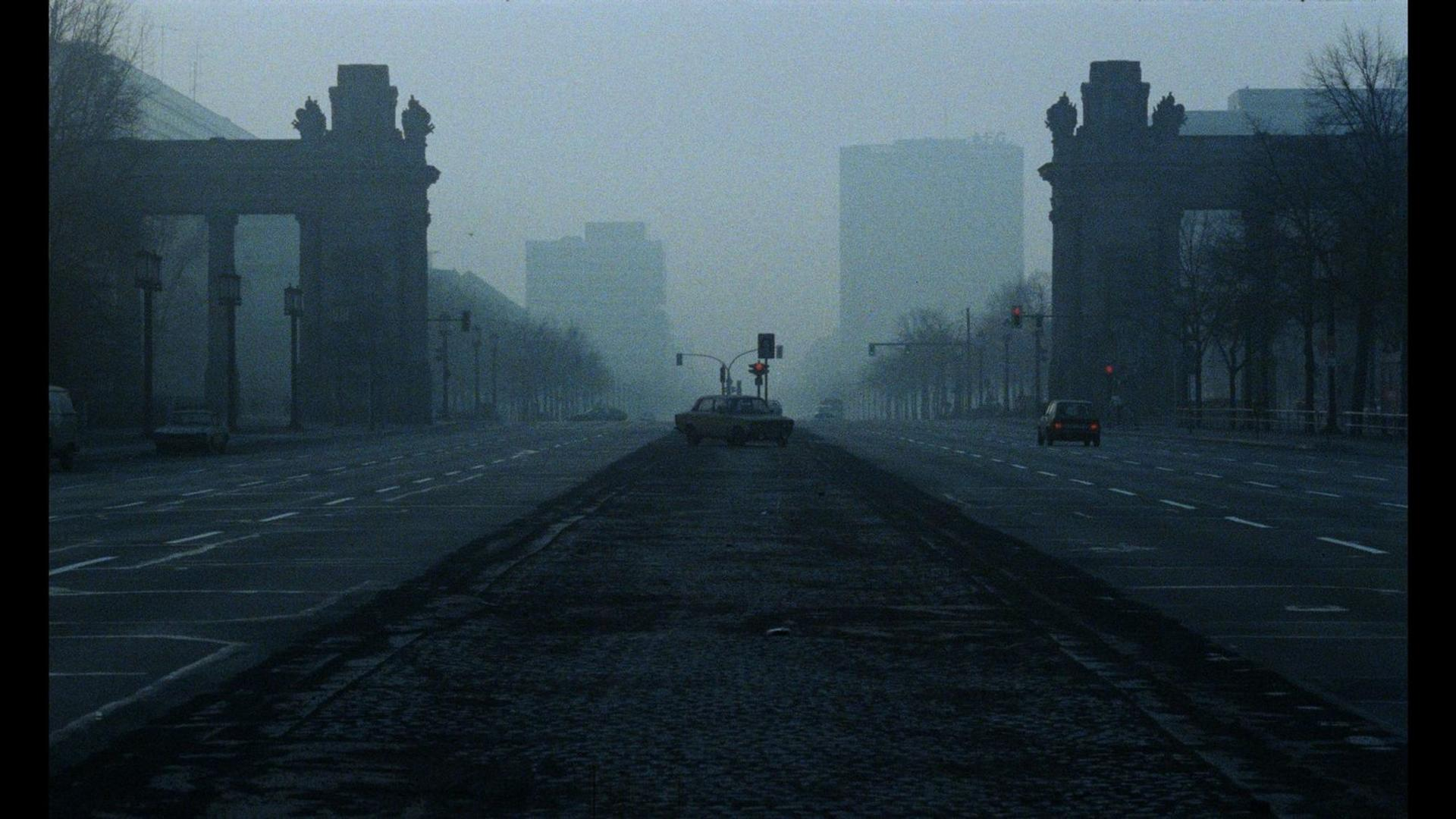 Eine neblige Straße mit Autos und Gebäuden im Hintergrund.