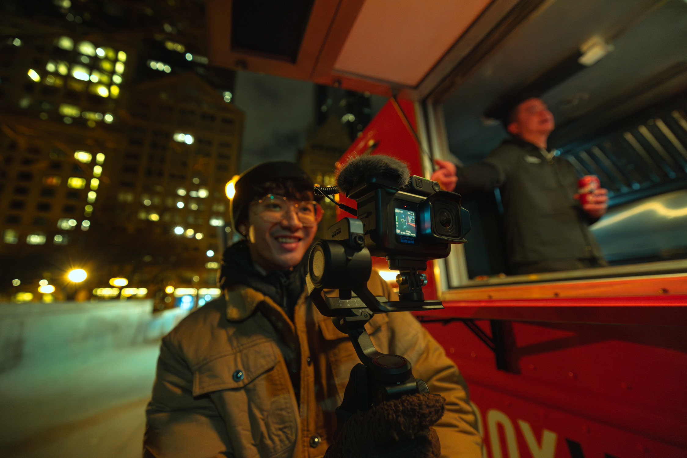 Ein Mann filmt mit einer Kamera auf einem Gimbal vor einem Foodtruck in der Nacht.