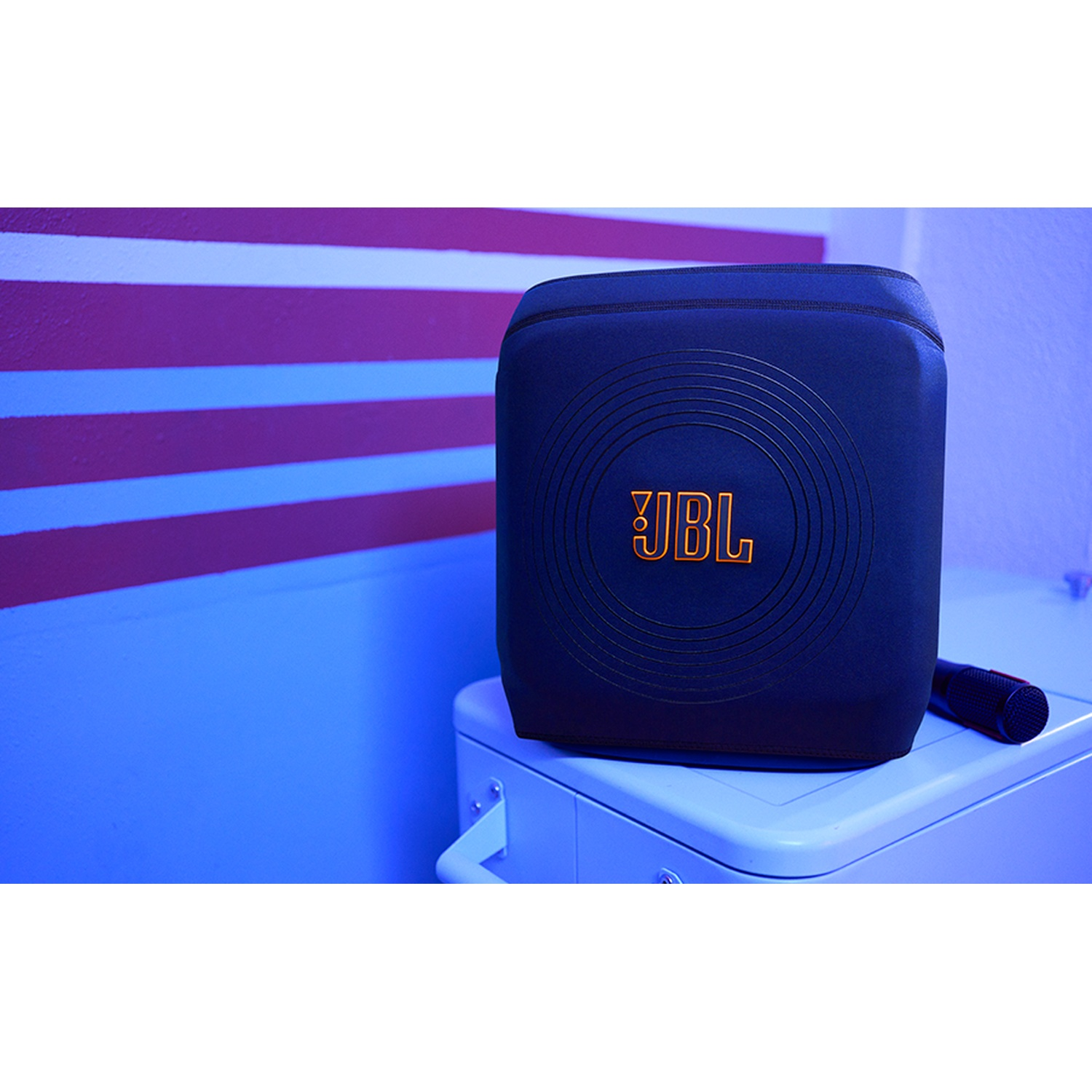 Een blauwe JBL speaker met oranje logo staat op een witte doos.