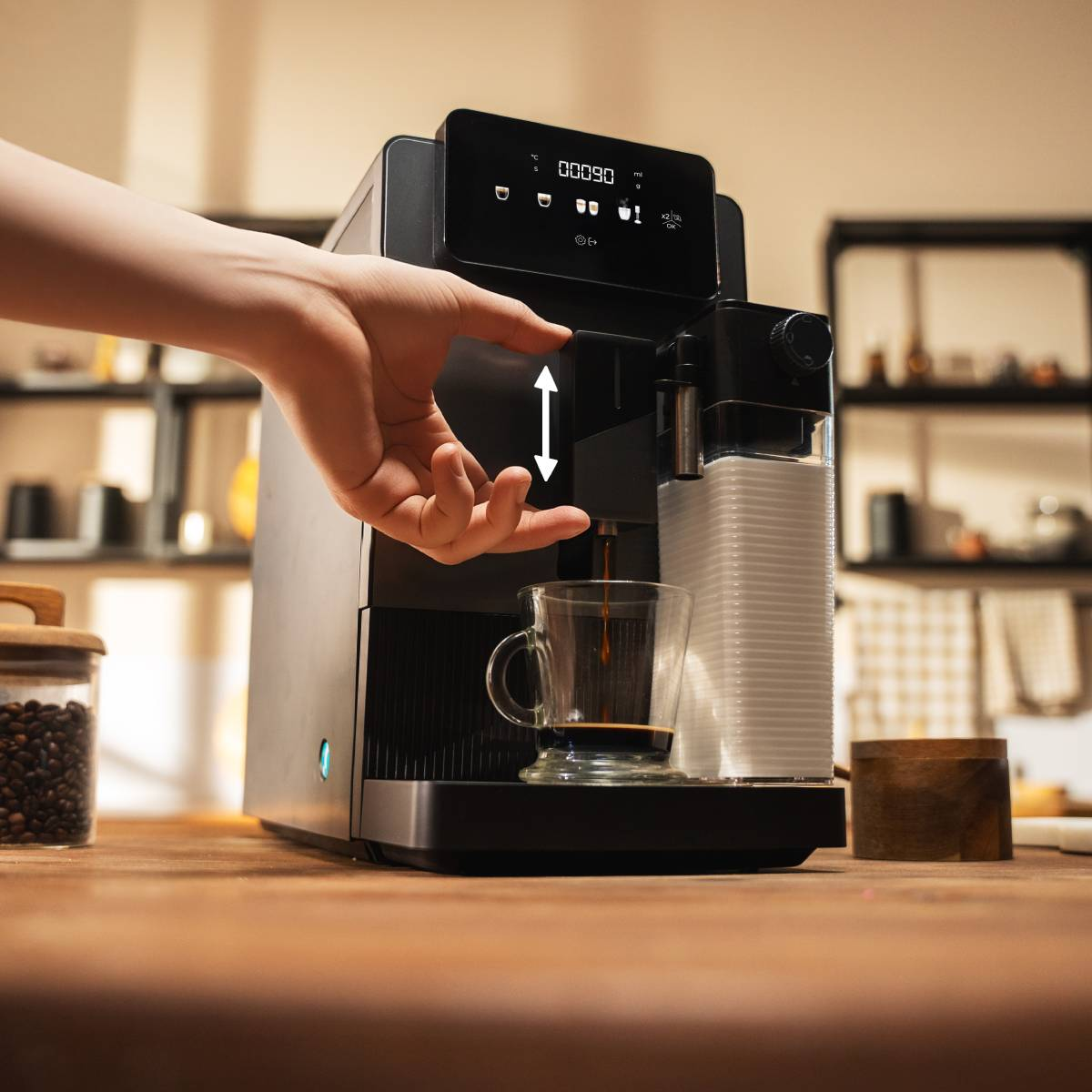Una mano opera una cafetera que prepara café en una taza.
